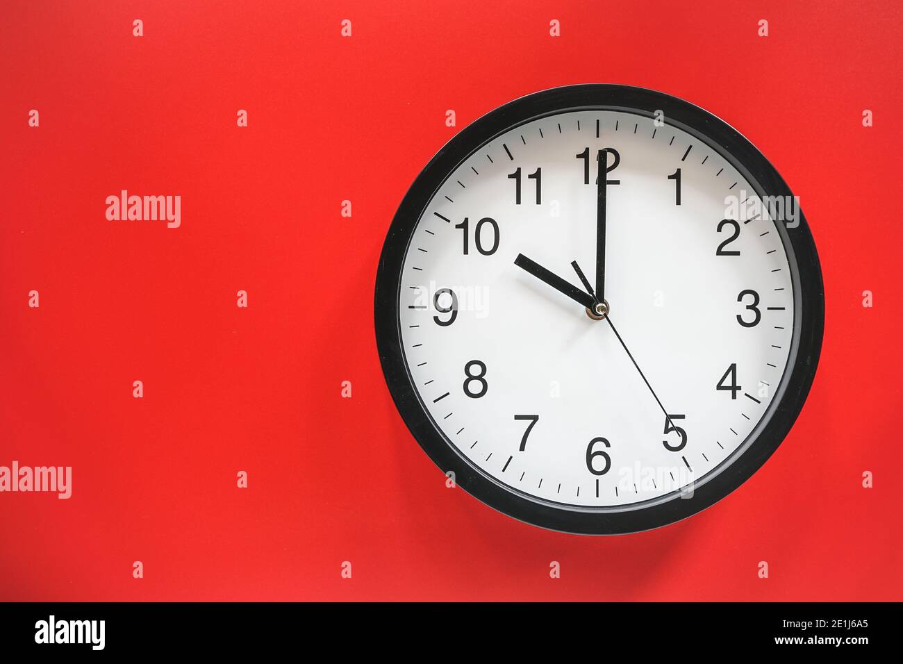 Classic black and white analog clock on red background at Ten o’clock