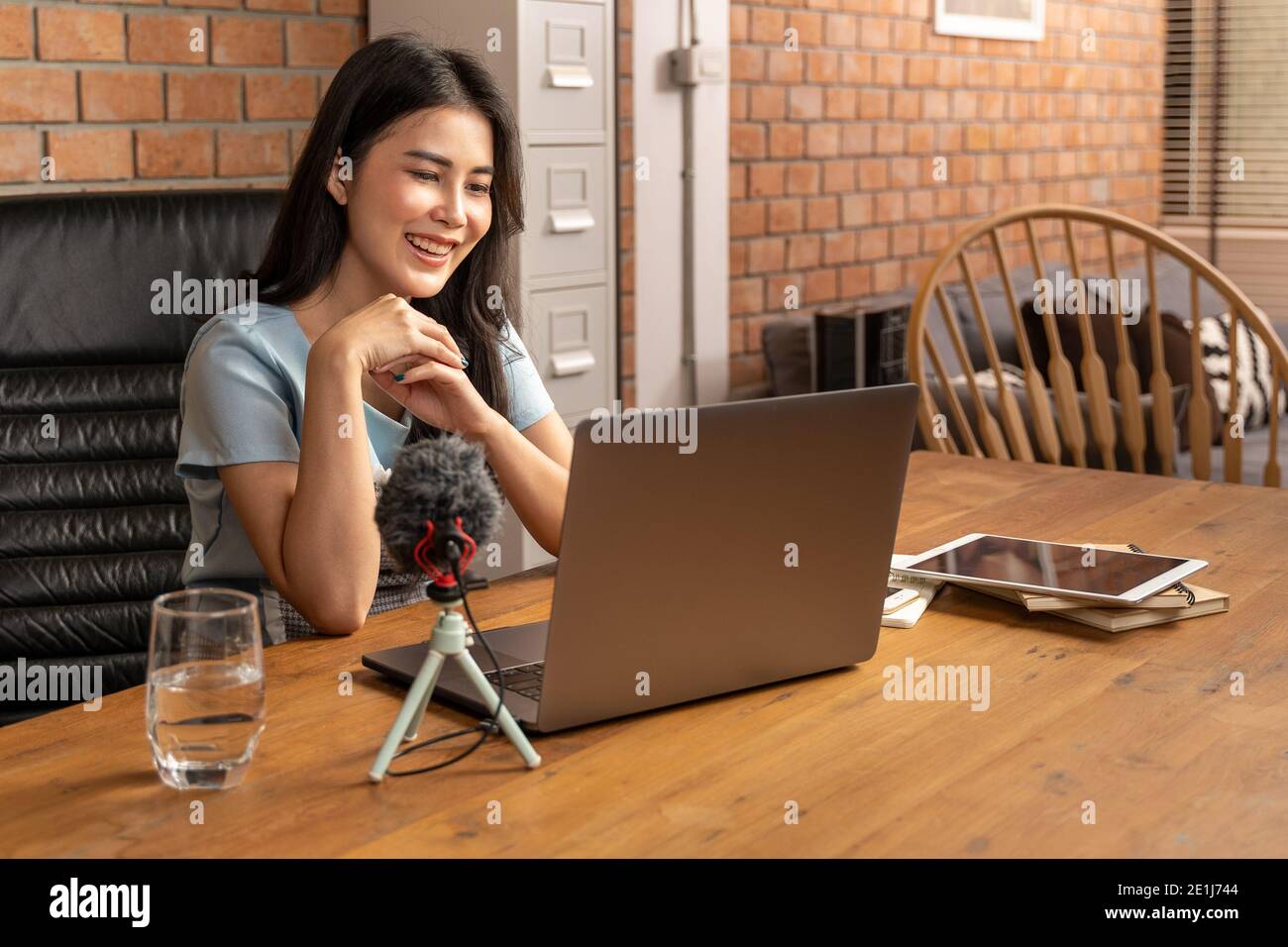 Happy young attractive woman working or learning online through her laptop computer at home in her living room during the pandamic lockdown, distant l Stock Photo