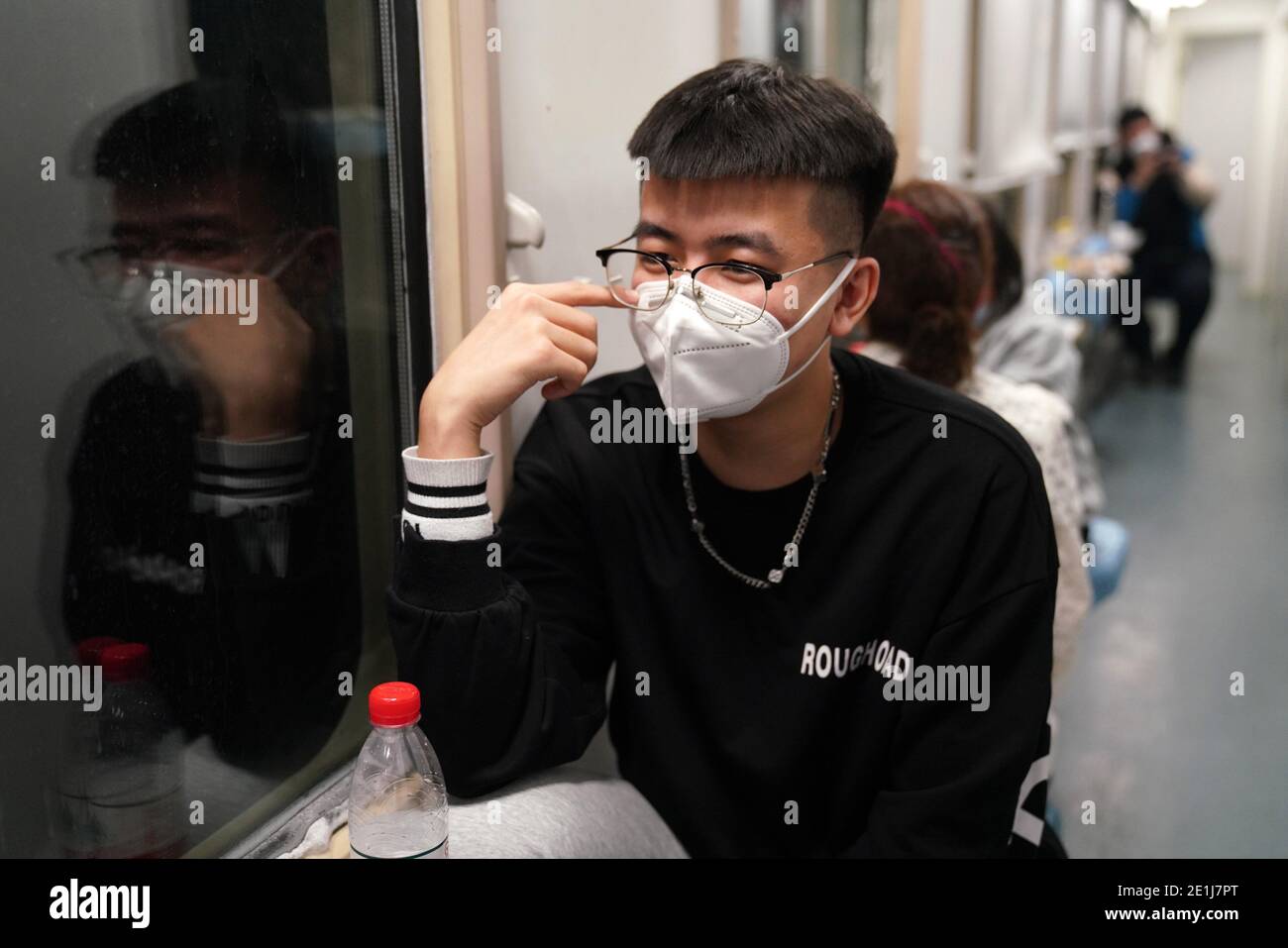 (210107) -- HARBIN, Jan. 7, 2021 (Xinhua) -- A passenger talks with his friend on train K7093 running from Harbin, northeast China's Heilongjiang Province to Hailar, north China's Inner Mongolia Autonomous Region, Jan. 6, 2021. Train No. K7093/4, connecting Harbin and Hailar, runs a distance of 1,320 kilometers and stops at 52 stations during the about 26-hour trip. The train stops every 30 minutes on average due to so many stops and is known as the slowest train in the forest area between the two destinations. Having operated for over 30 years, the train's facilities have witnessed upgrade an Stock Photo