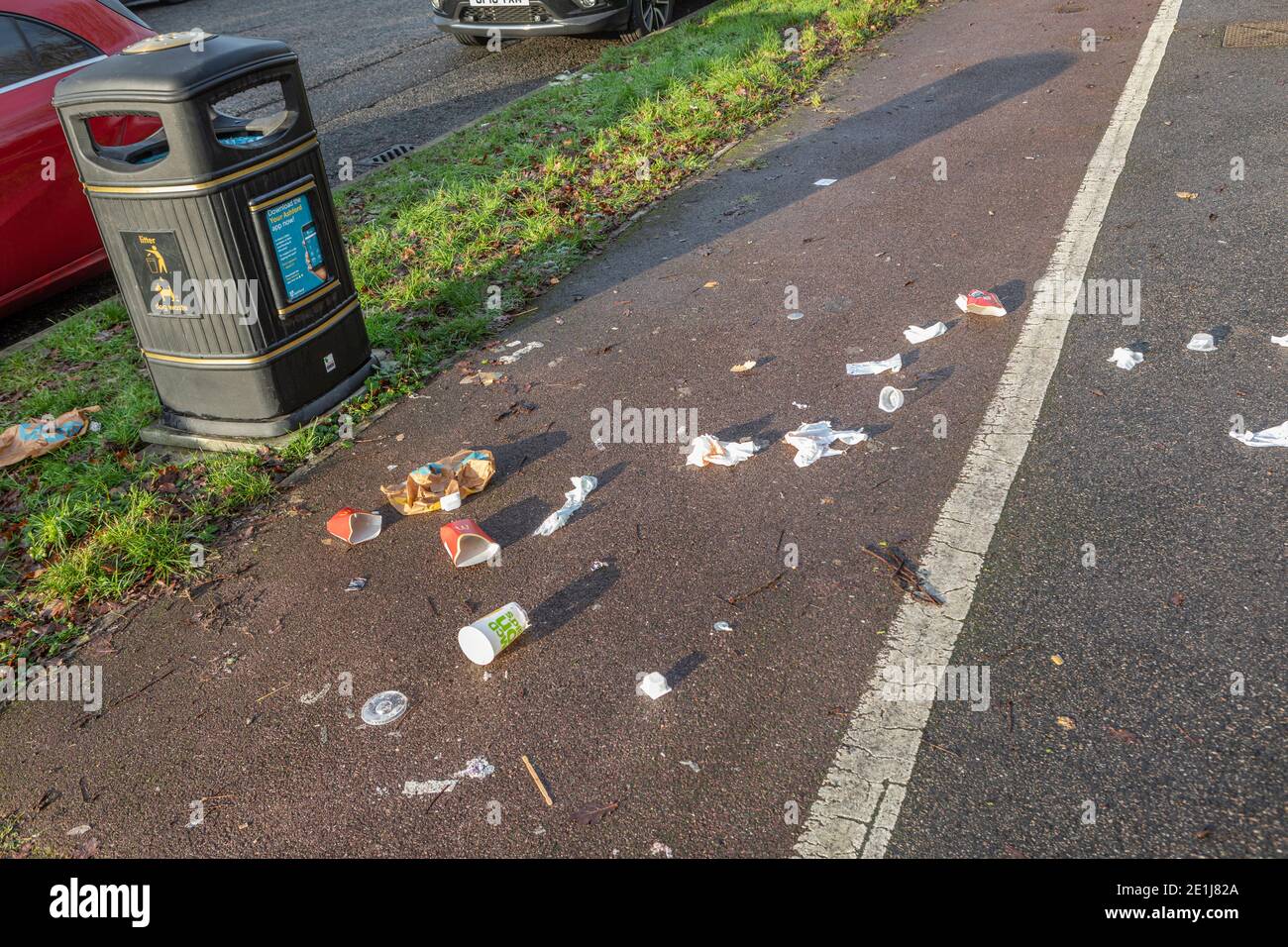 Refuse on a footpath near a rubbish bin. Stock Photo