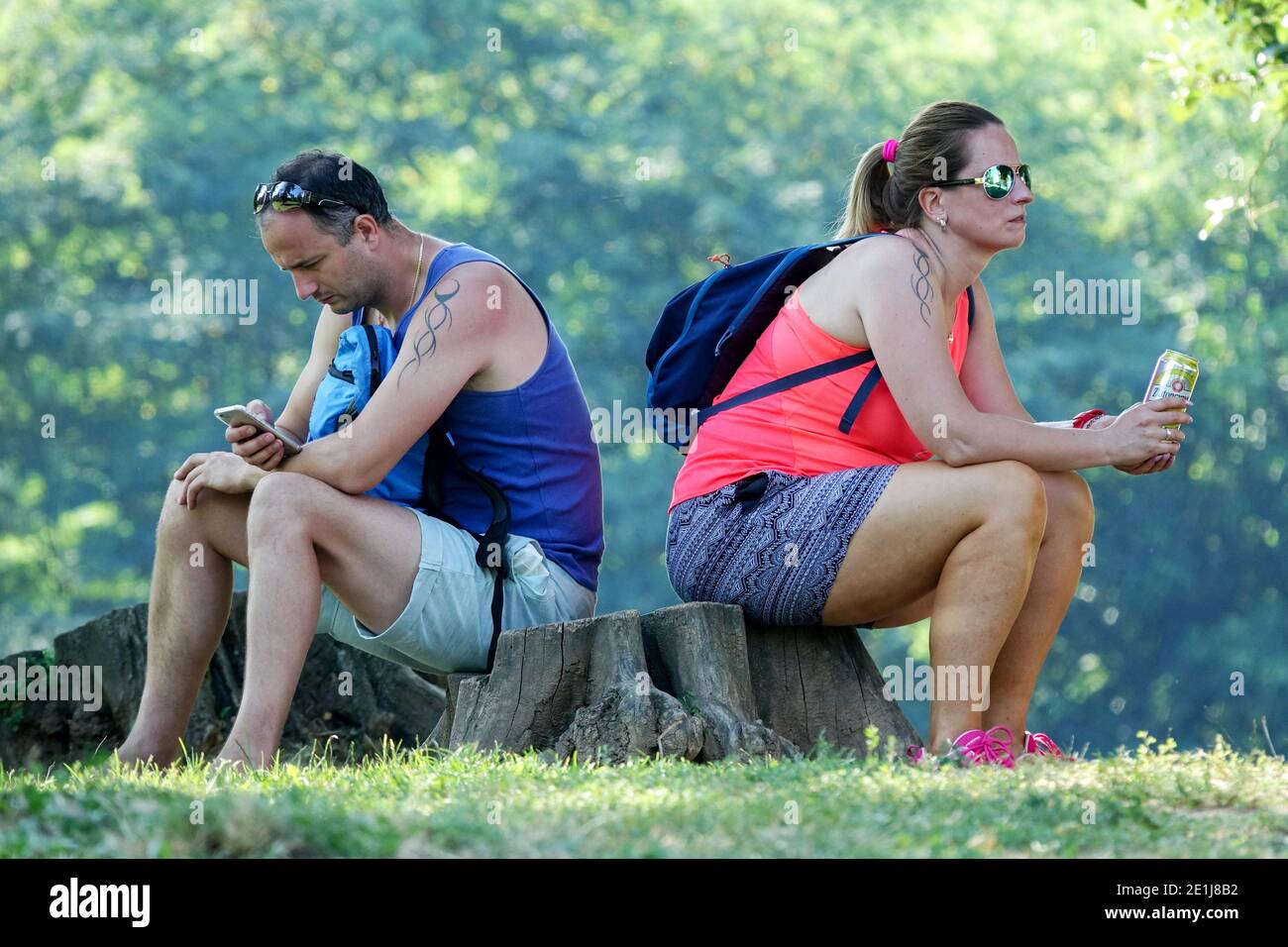 Couple vacation trip to nature A man and a woman sitting on a stump back to back couple Stock Photo