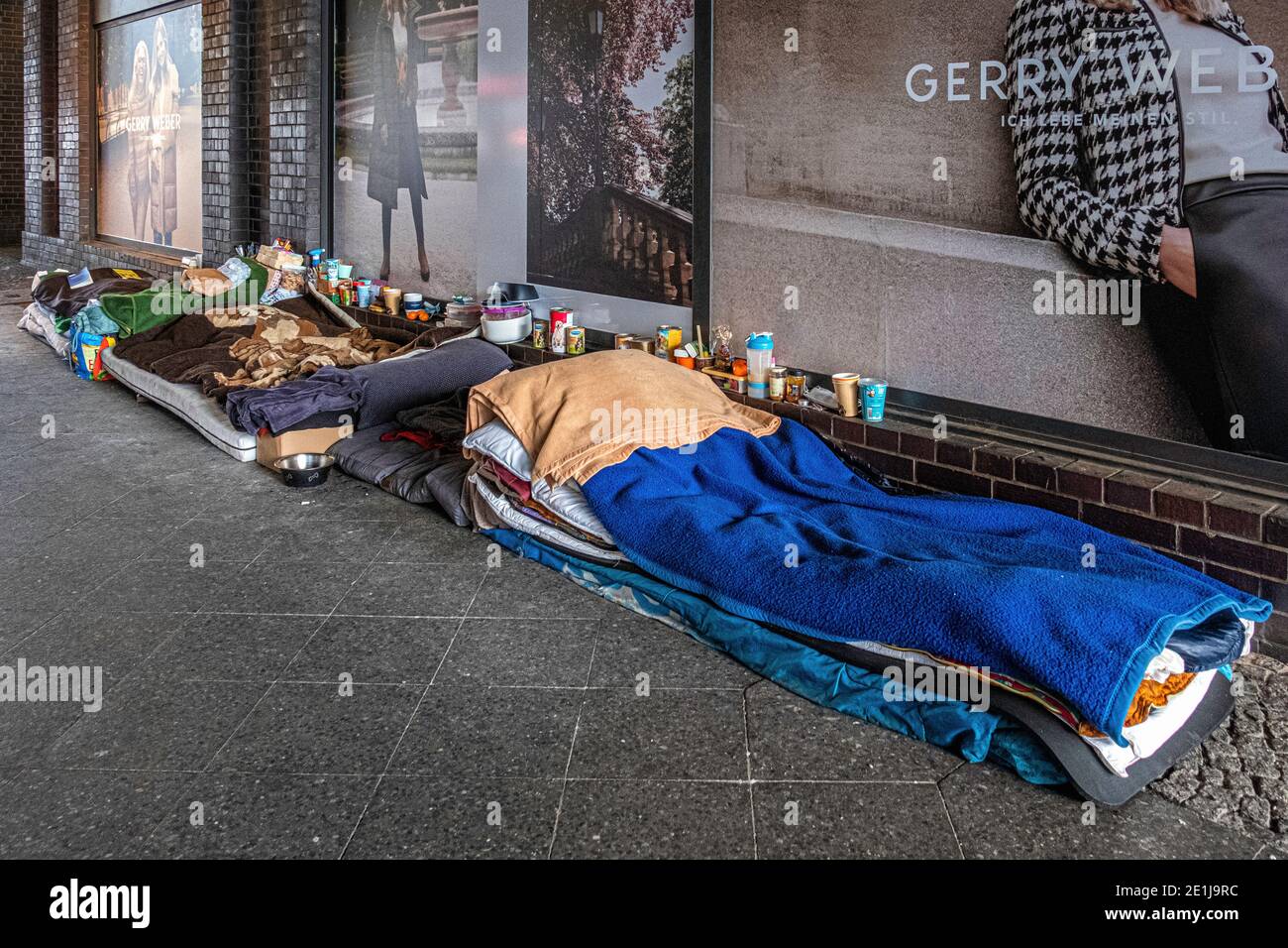 Possessions of the homeless on pavement outside Friedrichstrasse railway station, Mitte,Berlin. Beds, bedding & food supplies on pavement Stock Photo