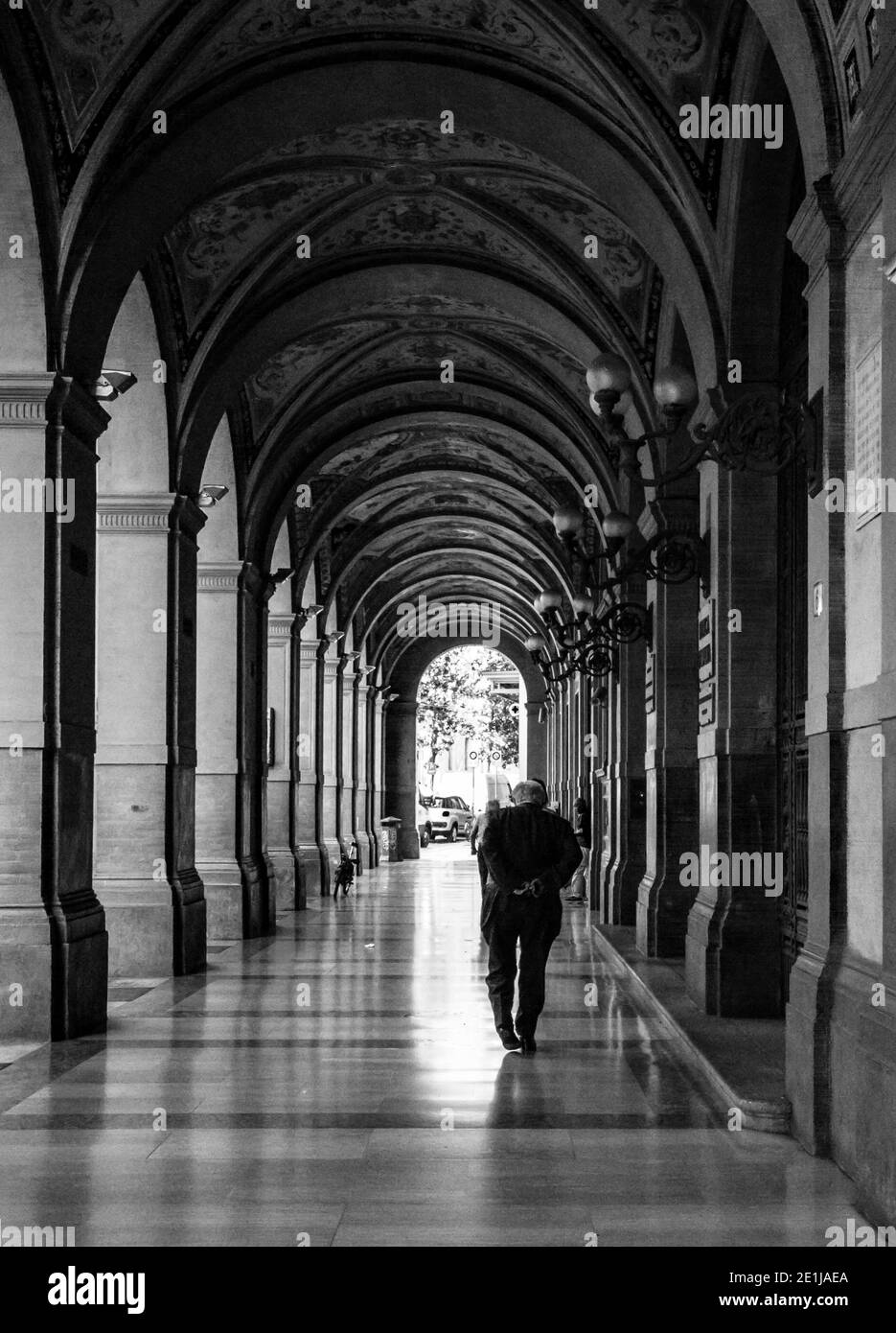 old man walking under the arcades in Bologna Stock Photo