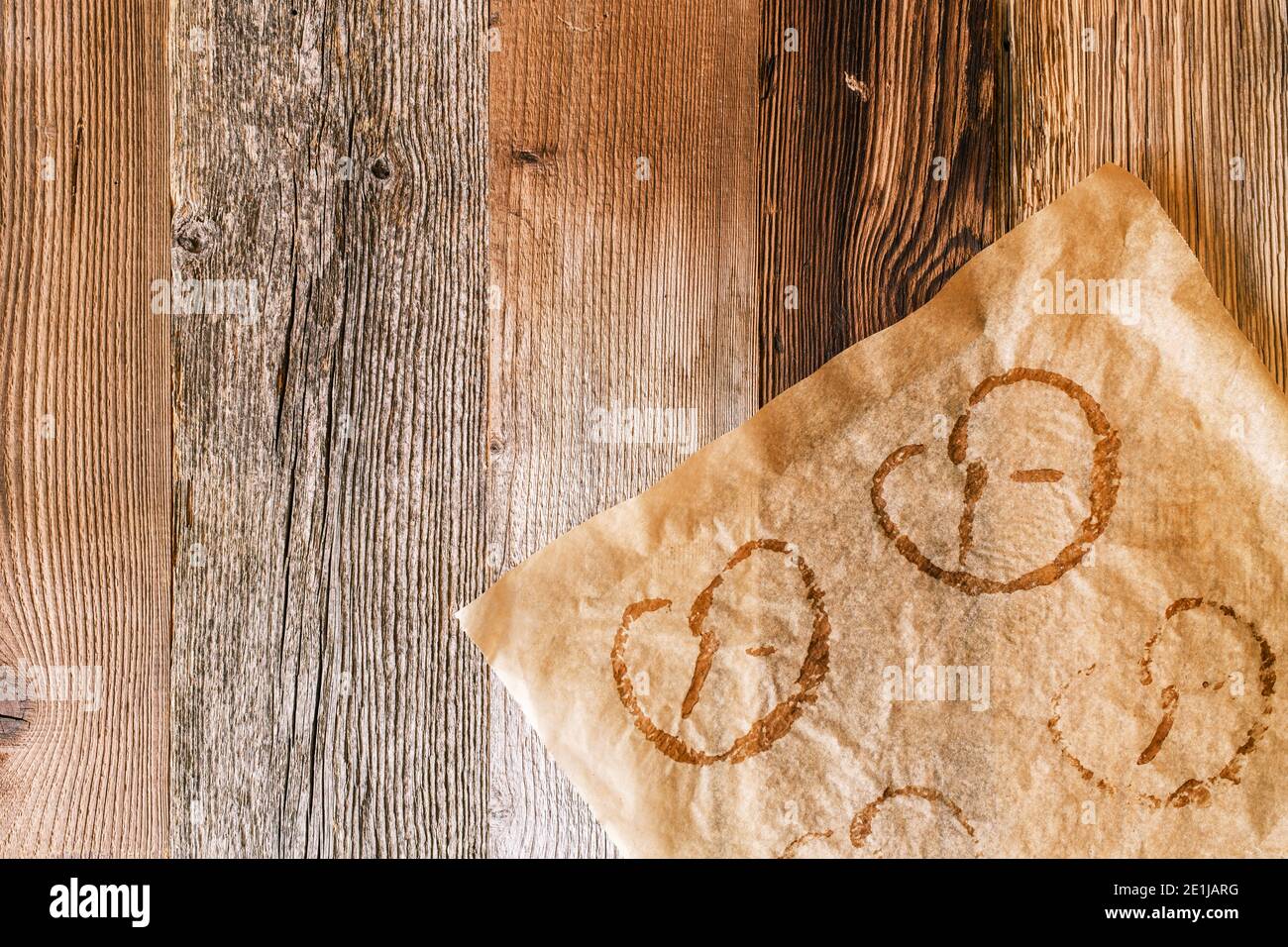 Used baking paper with imprints of baked pretzels on a rustic wooden background. Pretzels are typical German food in Bavaria and at the Oktoberfest. Stock Photo
