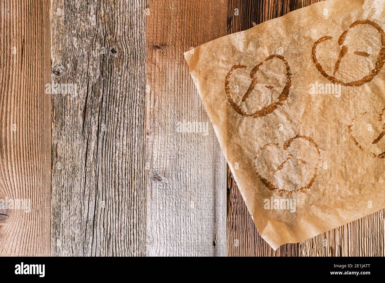 Used baking paper with imprints of baked pretzels on a rustic wooden background. Pretzels are typical German food in Bavaria and at the Oktoberfest. Stock Photo