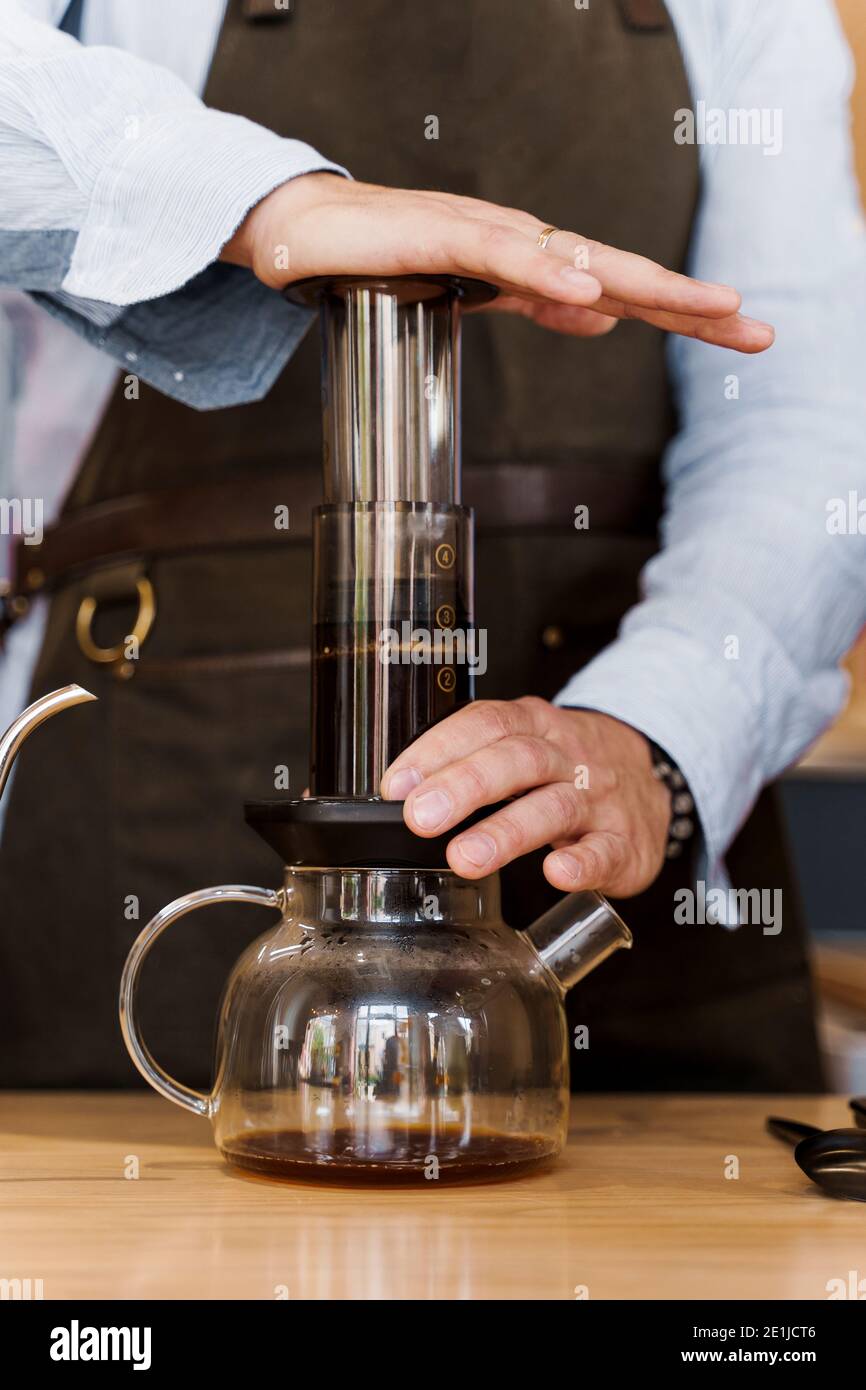Aeropress coffee close-up: barista press to device and coffee drops pours  trought aeropress to pot. Alternative coffee brewing method. Vertical photo  Stock Photo - Alamy