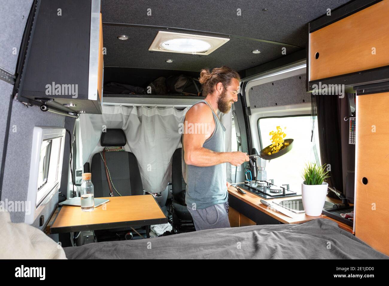 Man inside a camper van is cooking on a gas stove Stock Photo
