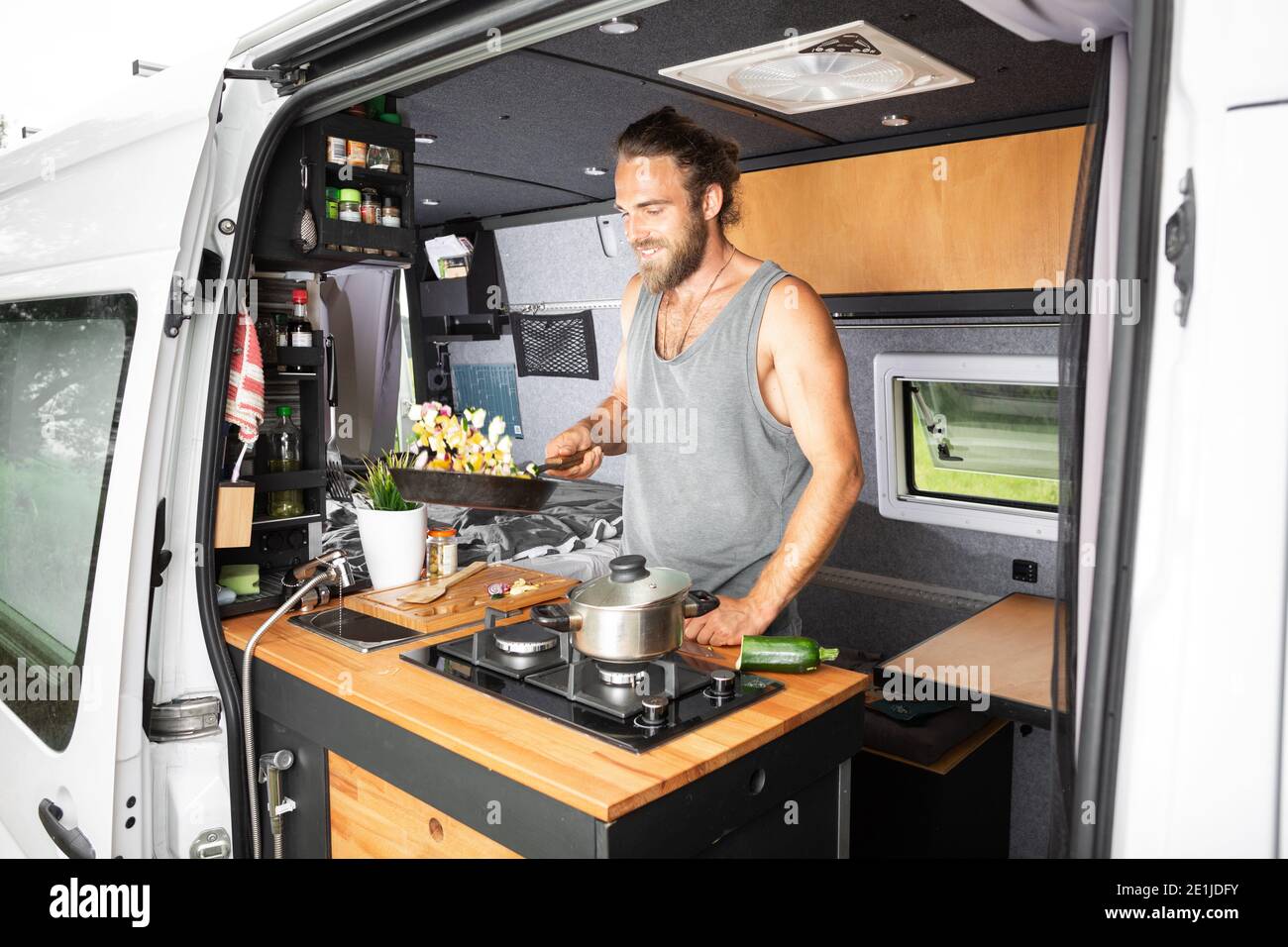 Smiling man cooking inside his camper van Stock Photo