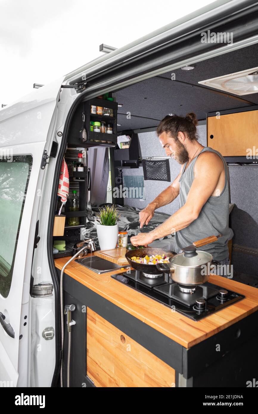 Man cooking inside his camper van Stock Photo