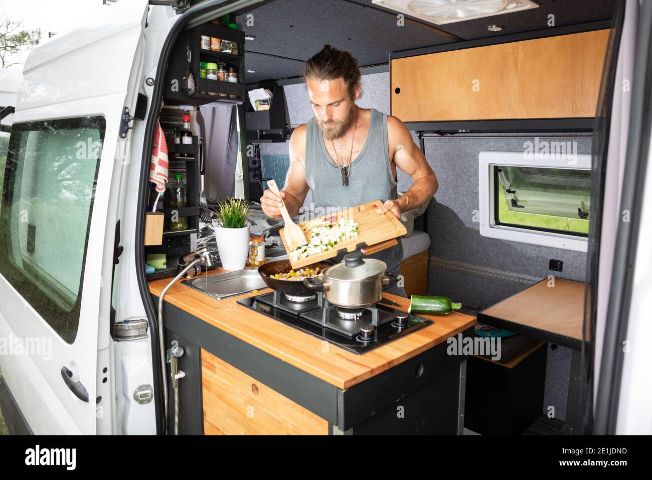 Young man cooking inside his camper van Stock Photo