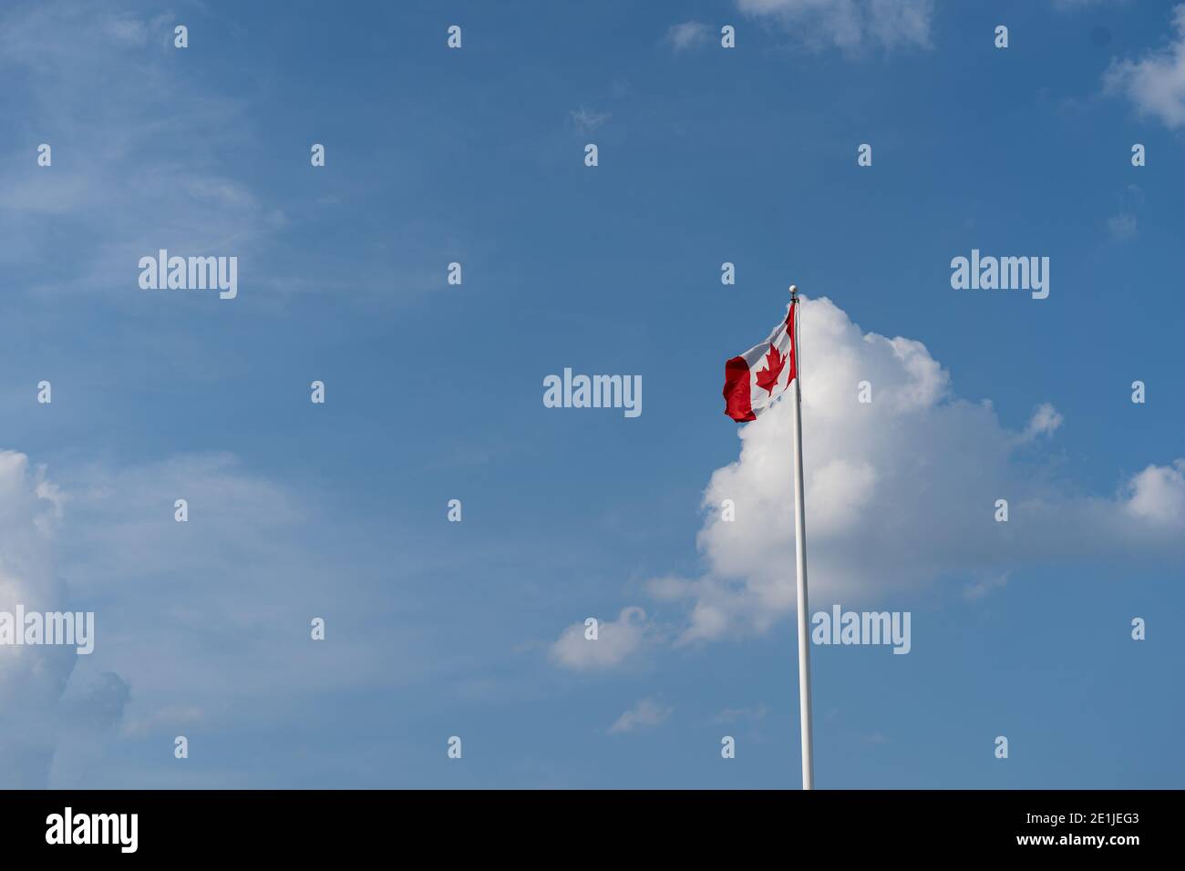 Canada Flag against blue sky with cloud. Seen from far Stock Photo