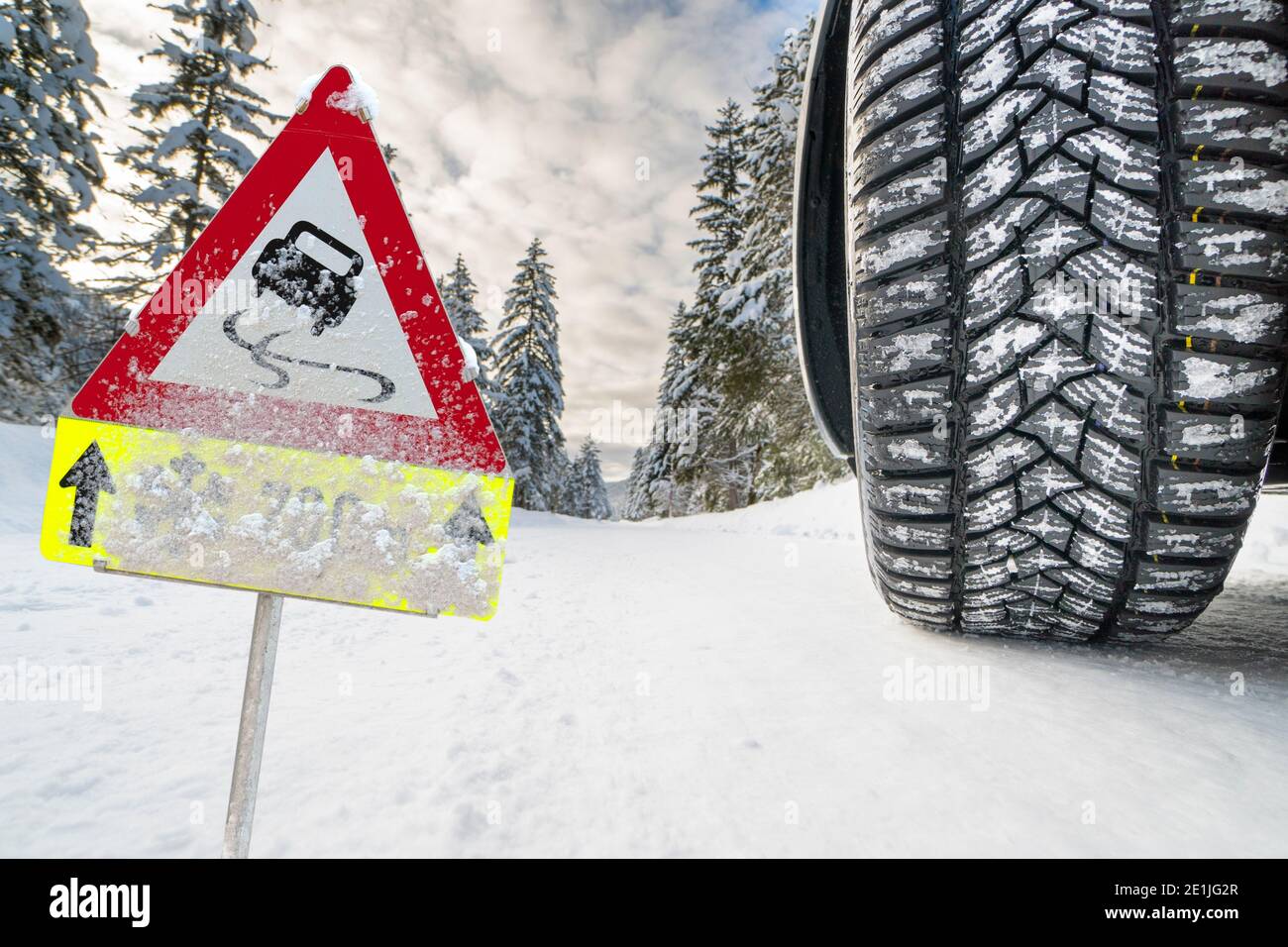 Winterreifen mit gutem Profil auf schneeglatter Straße und Warnschild Stock Photo