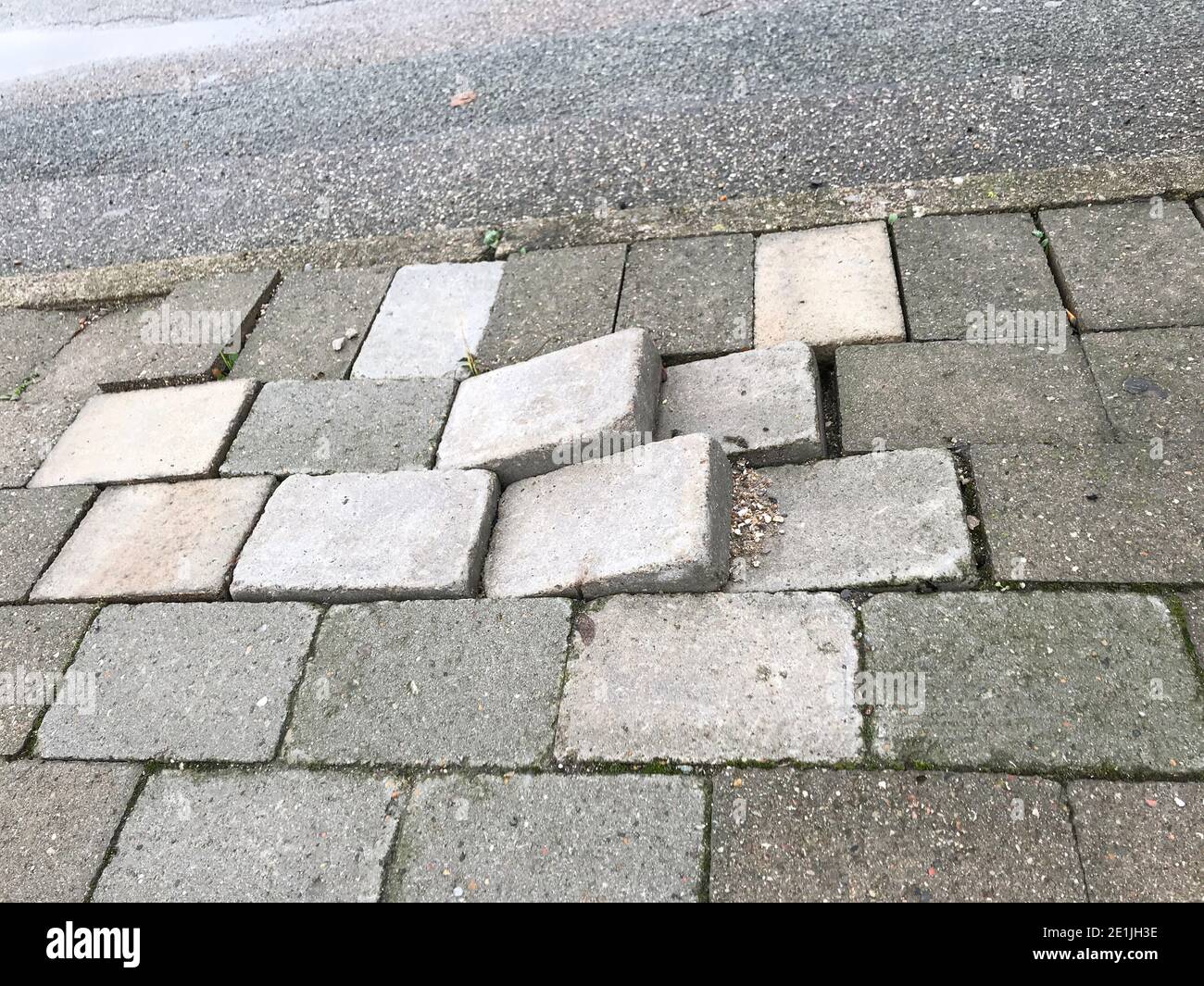 Sidewalk pavement tiles for pedestrians are uneven due to lack of maintenance can cause danger for pedestrians and traffic Stock Photo