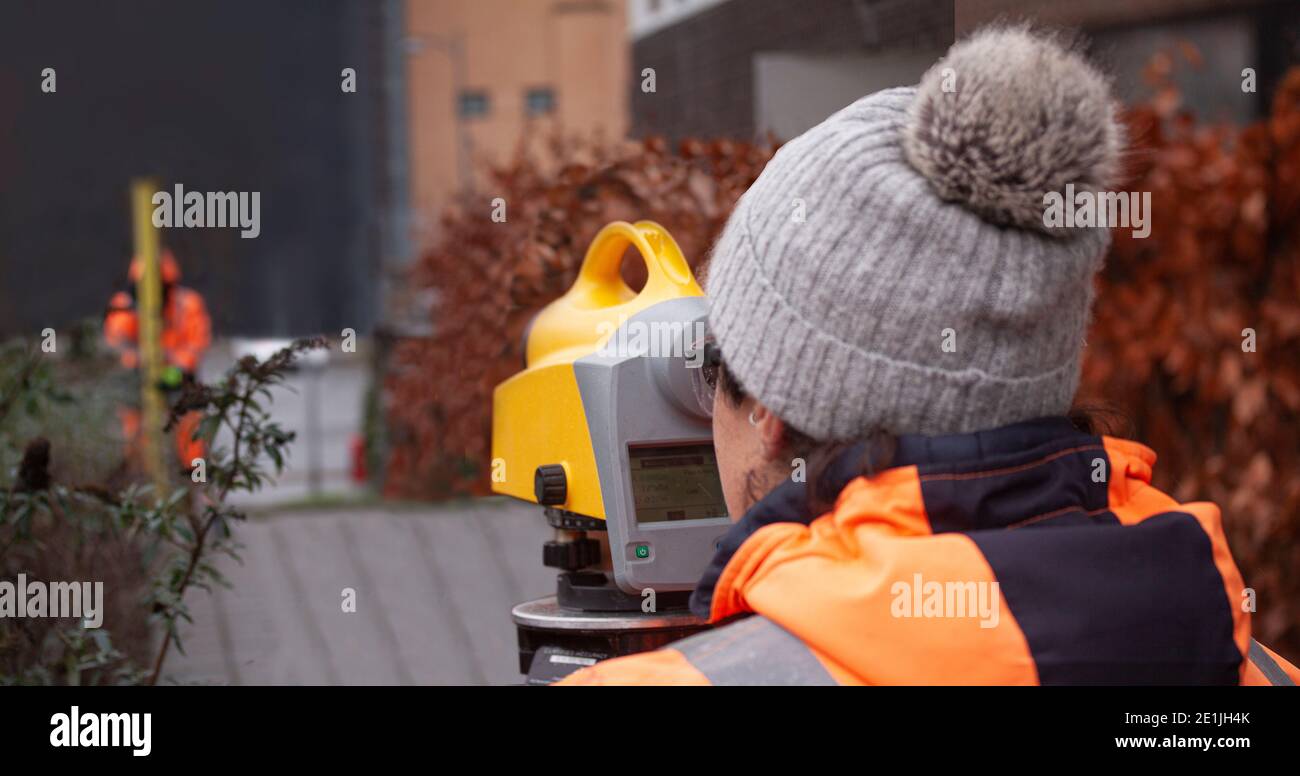 Female land surveyor operating a digital precision measurement level to establish or verify or measure the height of specified points relative to a da Stock Photo