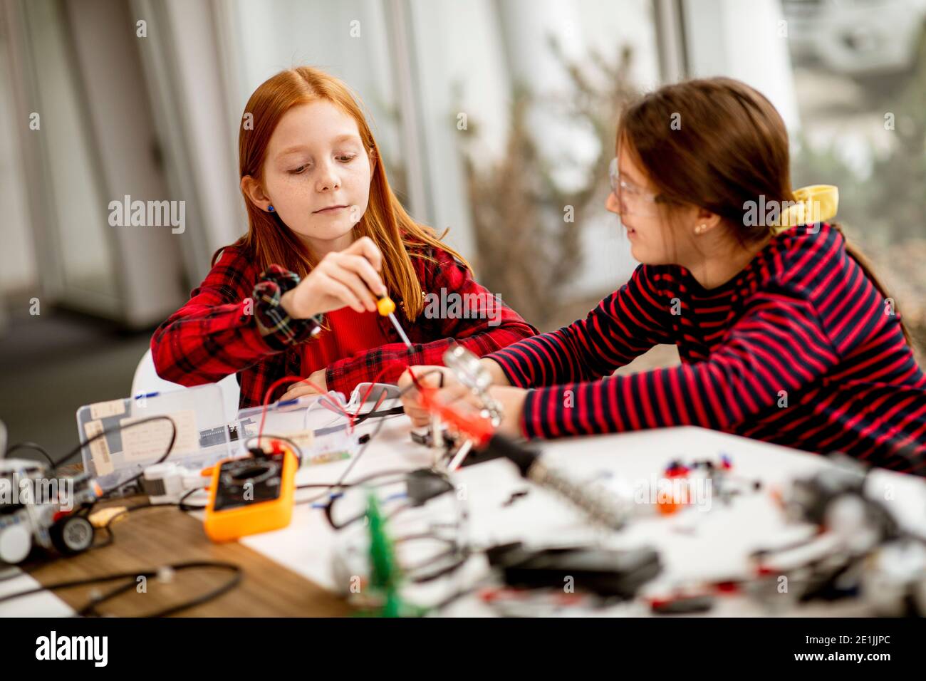 Group of cute little girls programming electric toys and robots at robotics classroom Stock Photo
