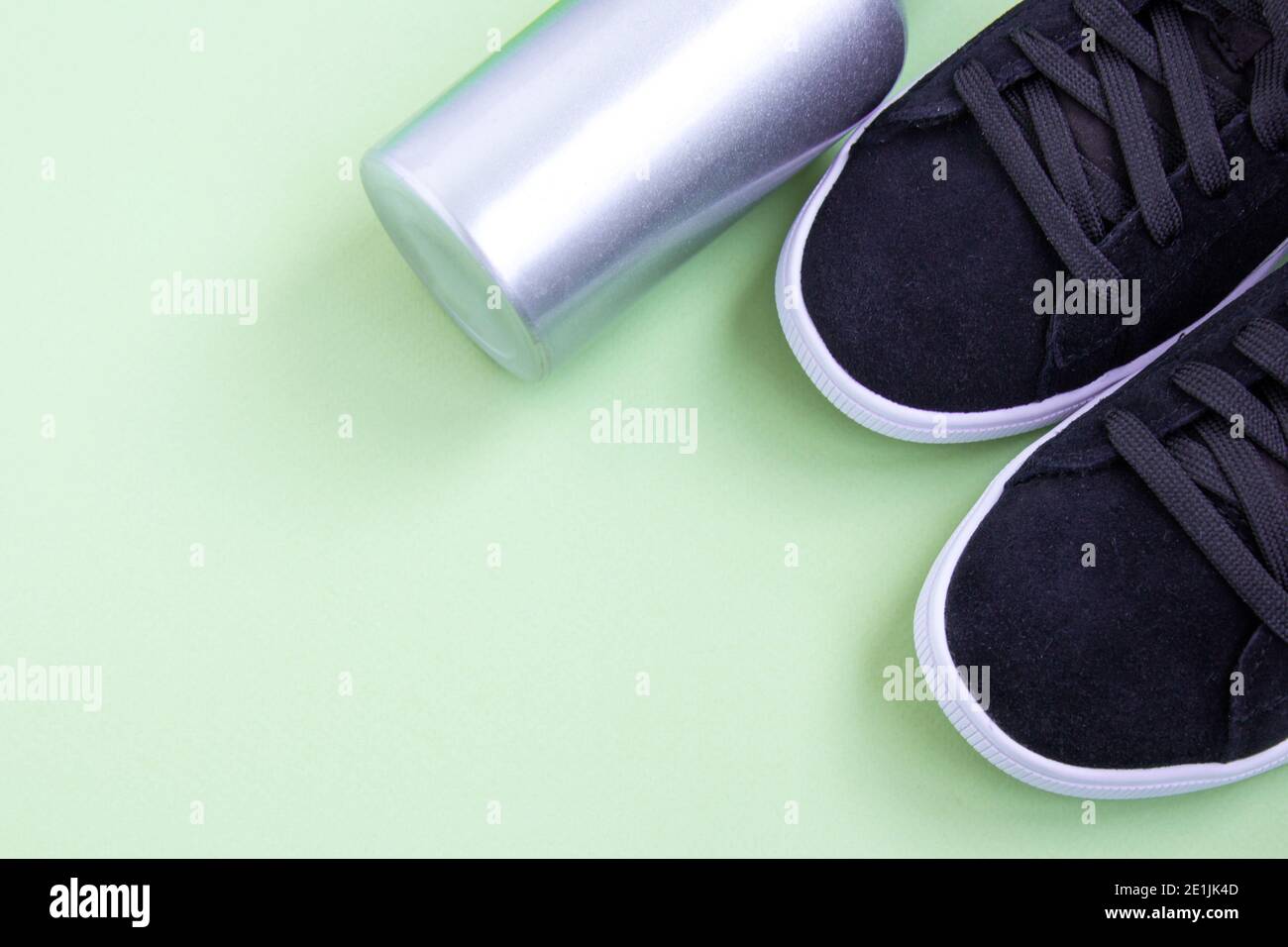 Black sneakers and iron bottle of water on green background. Concept of healthy lifestyle, everyday training. Shoes for women's training. Diagonal com Stock Photo