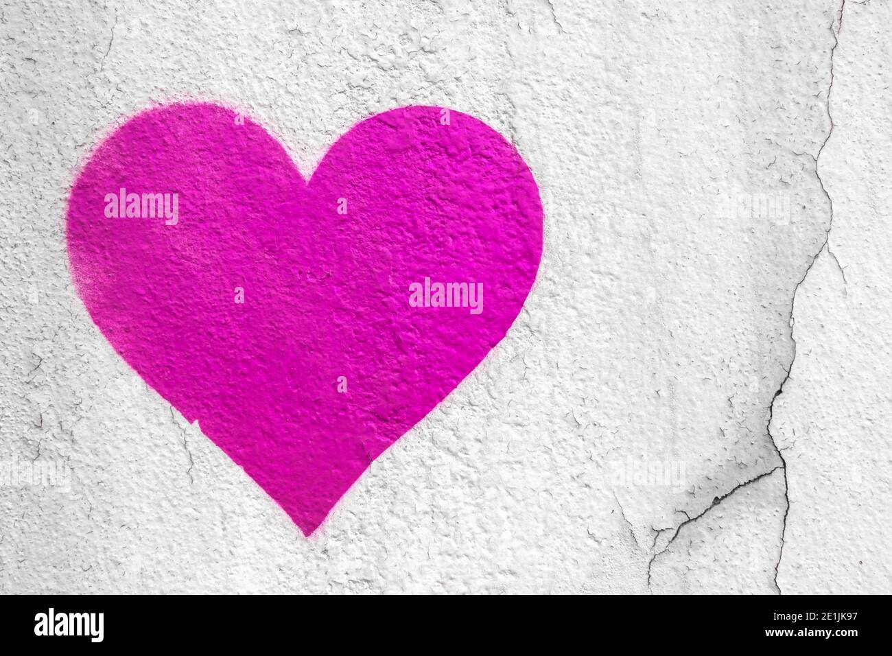 Pink love heart hand drawn on grungy wall. Textured background trendy street style. Stock Photo
