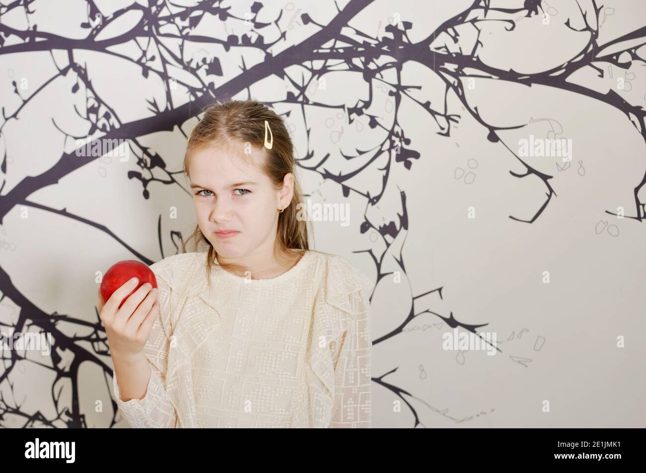 White Caucasian girl (child, kid) looking disgusting at an red apple. Copy text Stock Photo
