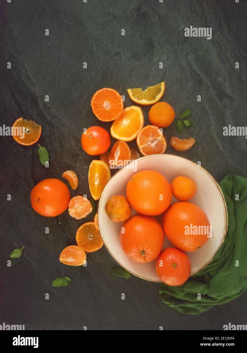 Whole and sliced oranges on a luxury dark background under the sunlight Stock Photo