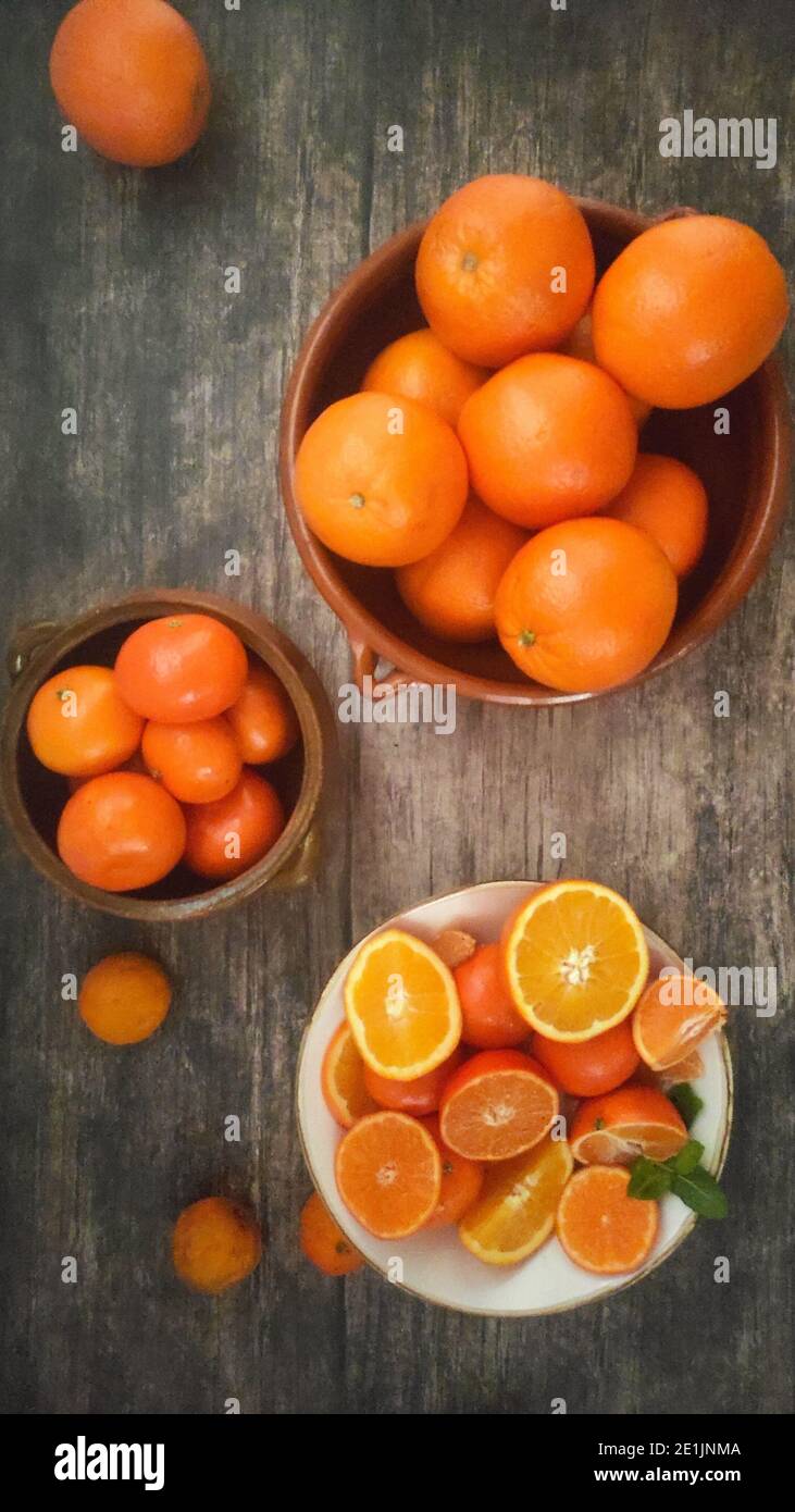 Oranges, mandarin oranges, tangerines, all citrus fruit in bowl and on a rural kitchen table Stock Photo