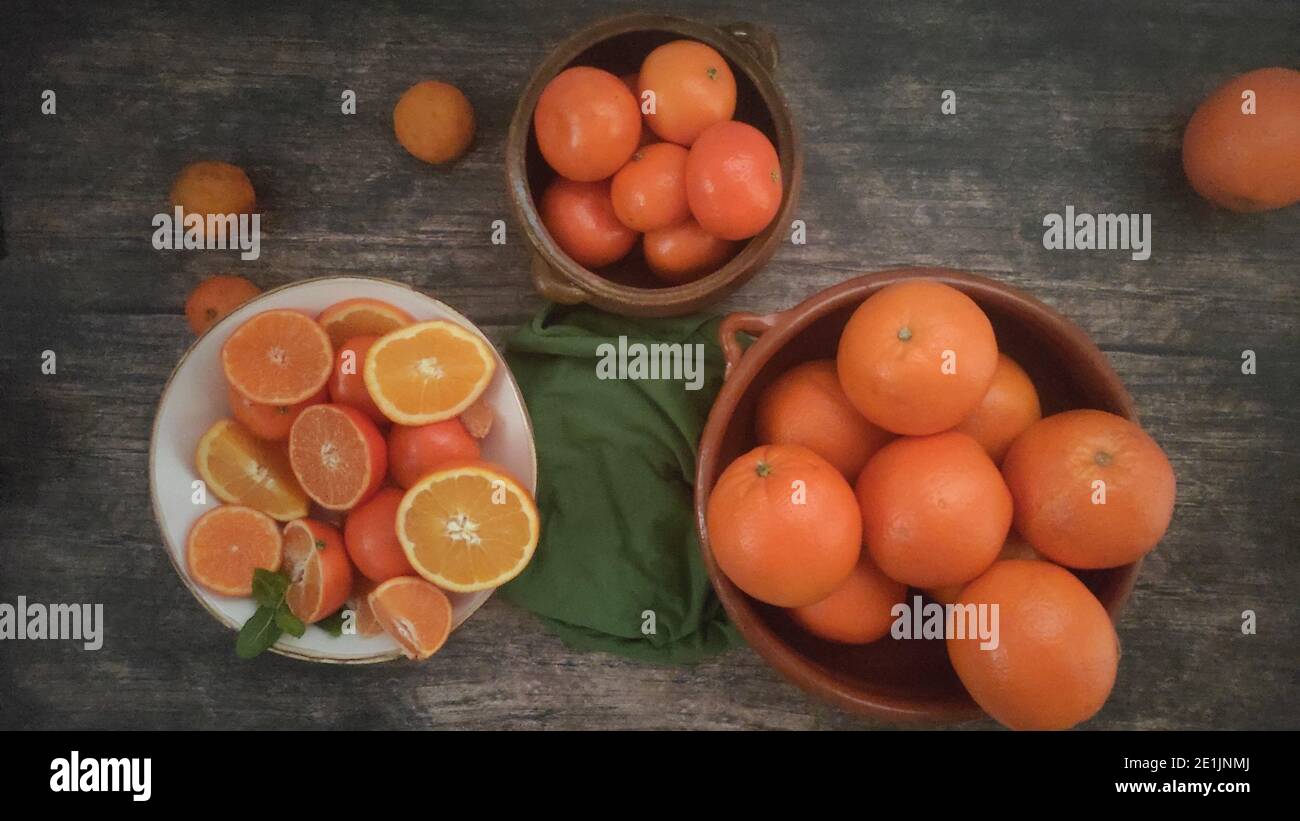 Oranges, mandarin oranges, tangerines, all citrus fruit in bowl and on a rural kitchen table Stock Photo