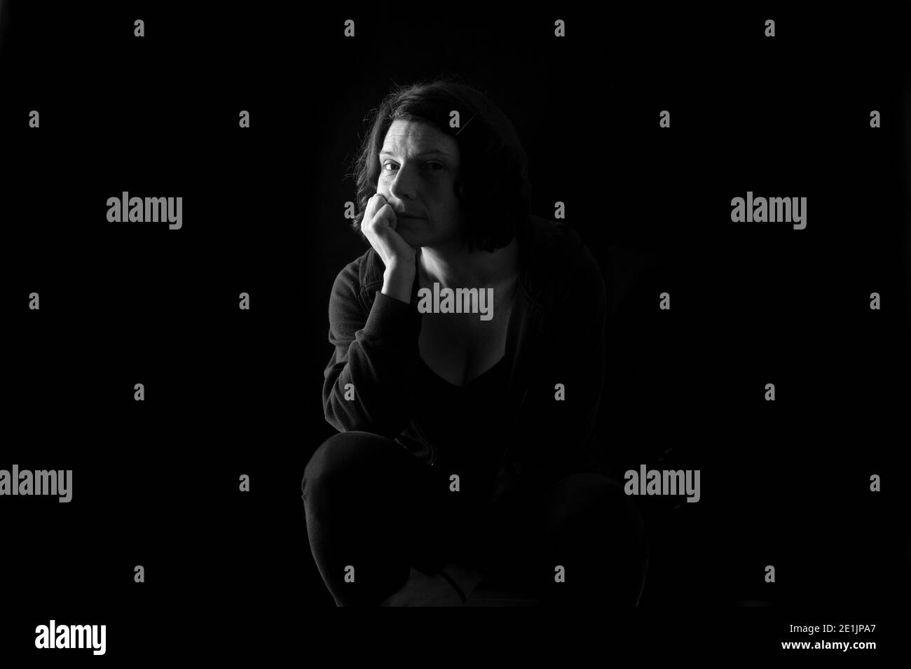 portrait of a woman sitting on black background Stock Photo