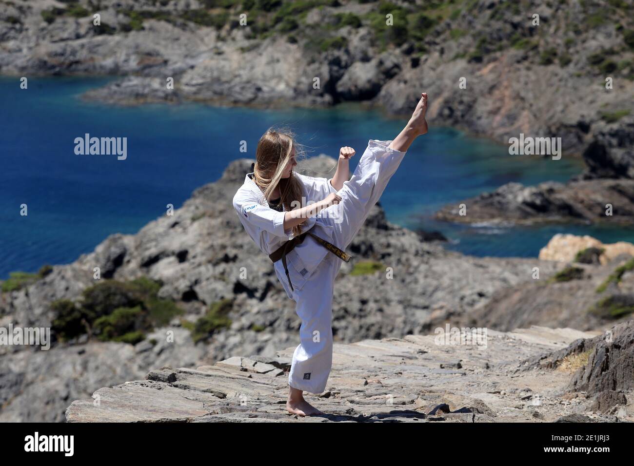 A girl in karate, training in the mountains, with a view of the sea Stock Photo