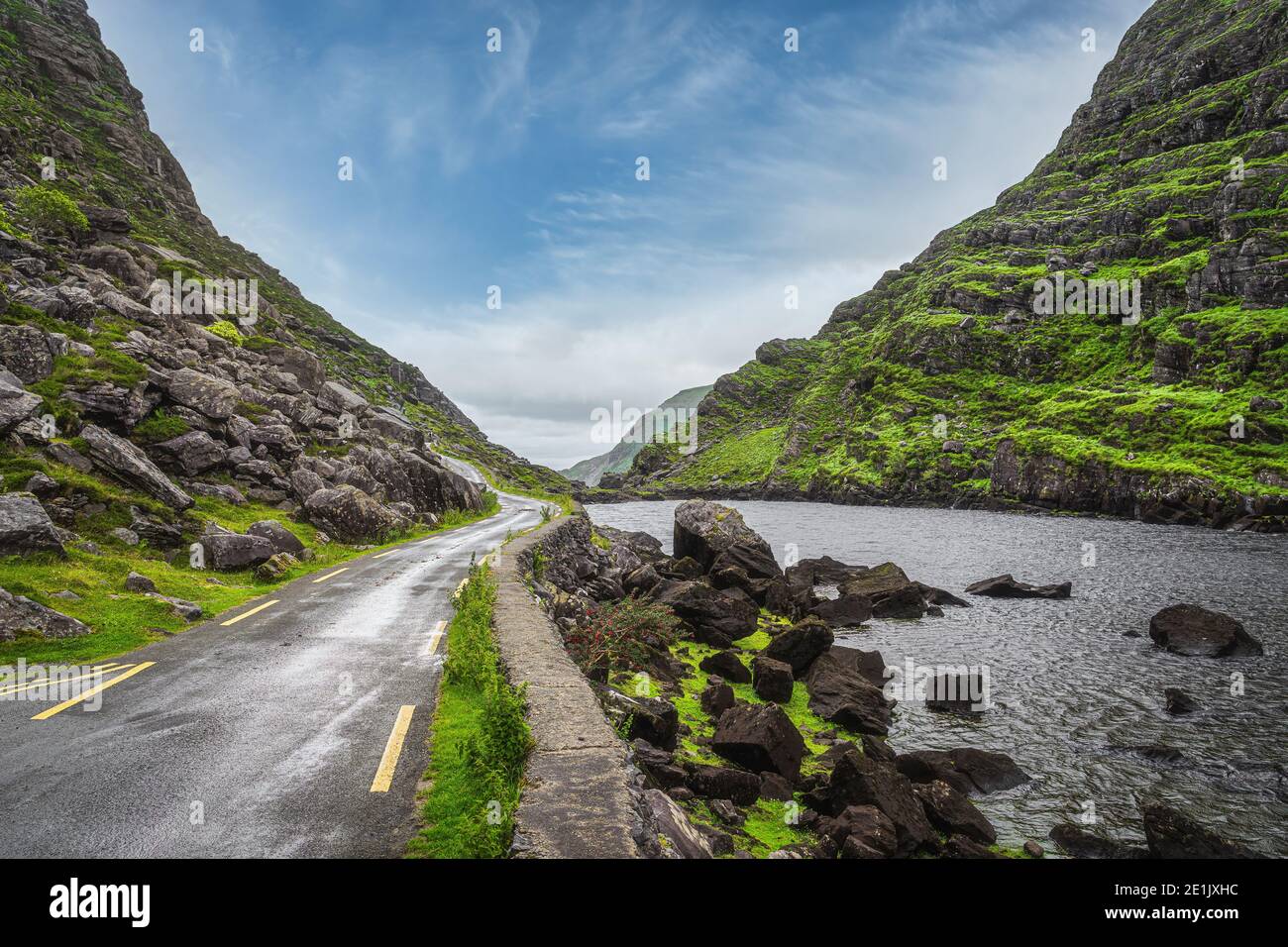 Narrow winding road running alongside lake and stream in green valley, Gap of Dunloe in Black Valley, Ring of Kerry, County Kerry, Ireland Stock Photo