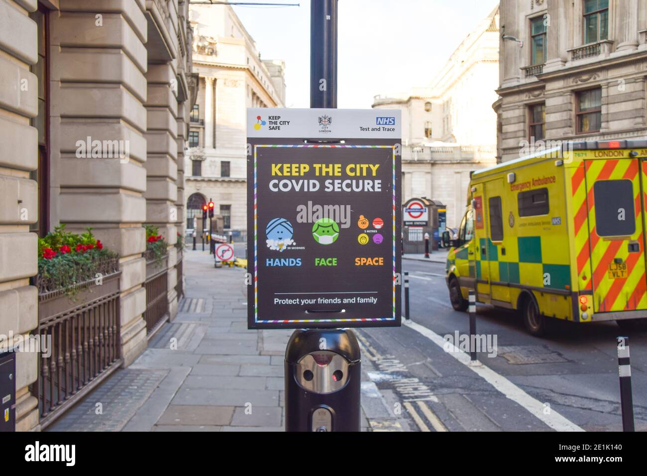 An ambulance drives past a 'Keep The City COVID Secure' Sign in City of London Stock Photo
