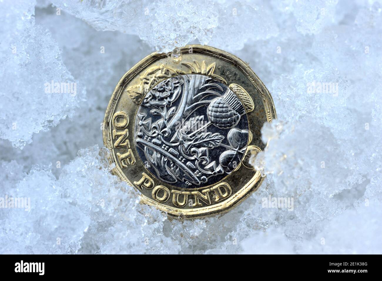 BRITISH ONE POUND COIN IN SNOW AND ICE RE THE ECONOMY WAGES INCOMES PENSIONS WINTER ETC UK Stock Photo
