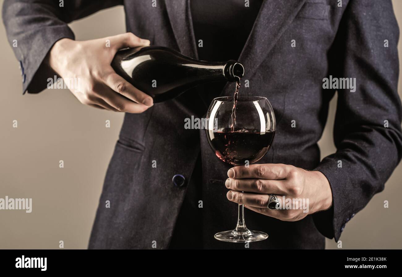 Gourmet drink bottle, red wine glass, sommelier, tasting. Waiter pouring red wine in a glass. Stock Photo