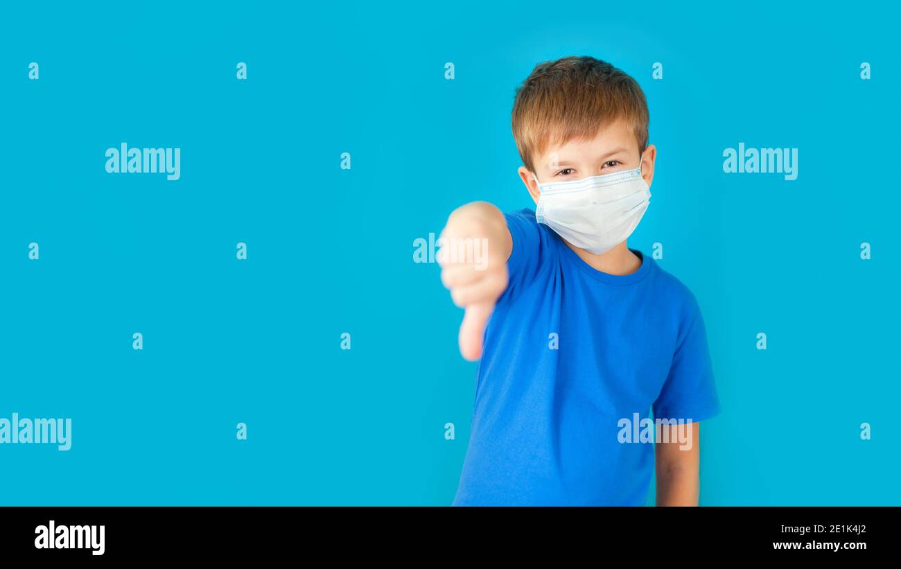 Cute boy with medical mask on his face showing hands with thumbs down ...