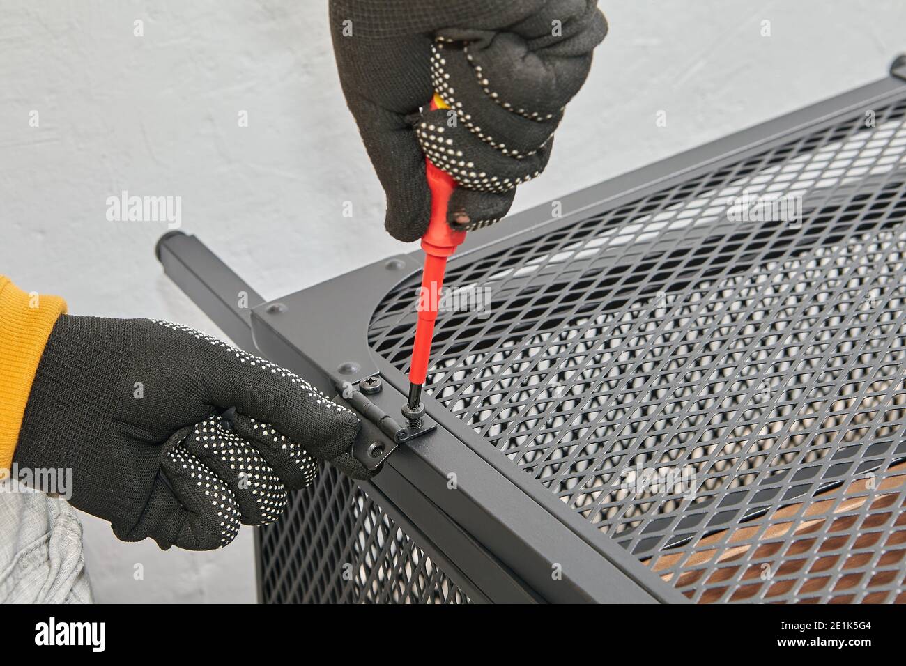 Installation of doors on a TV stand, carpenter screwing hinges Stock