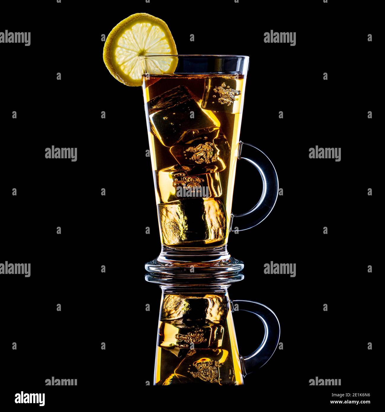 Iced tea with a slice of lemon in tall glass with handle on black background Stock Photo