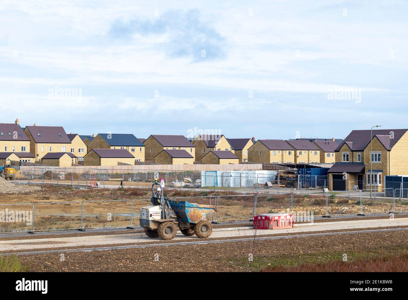 Builder working with dumper truck on a new housing development at West Witney on the outskirts of Oxford, West Oxfordshire, England due to population Stock Photo
