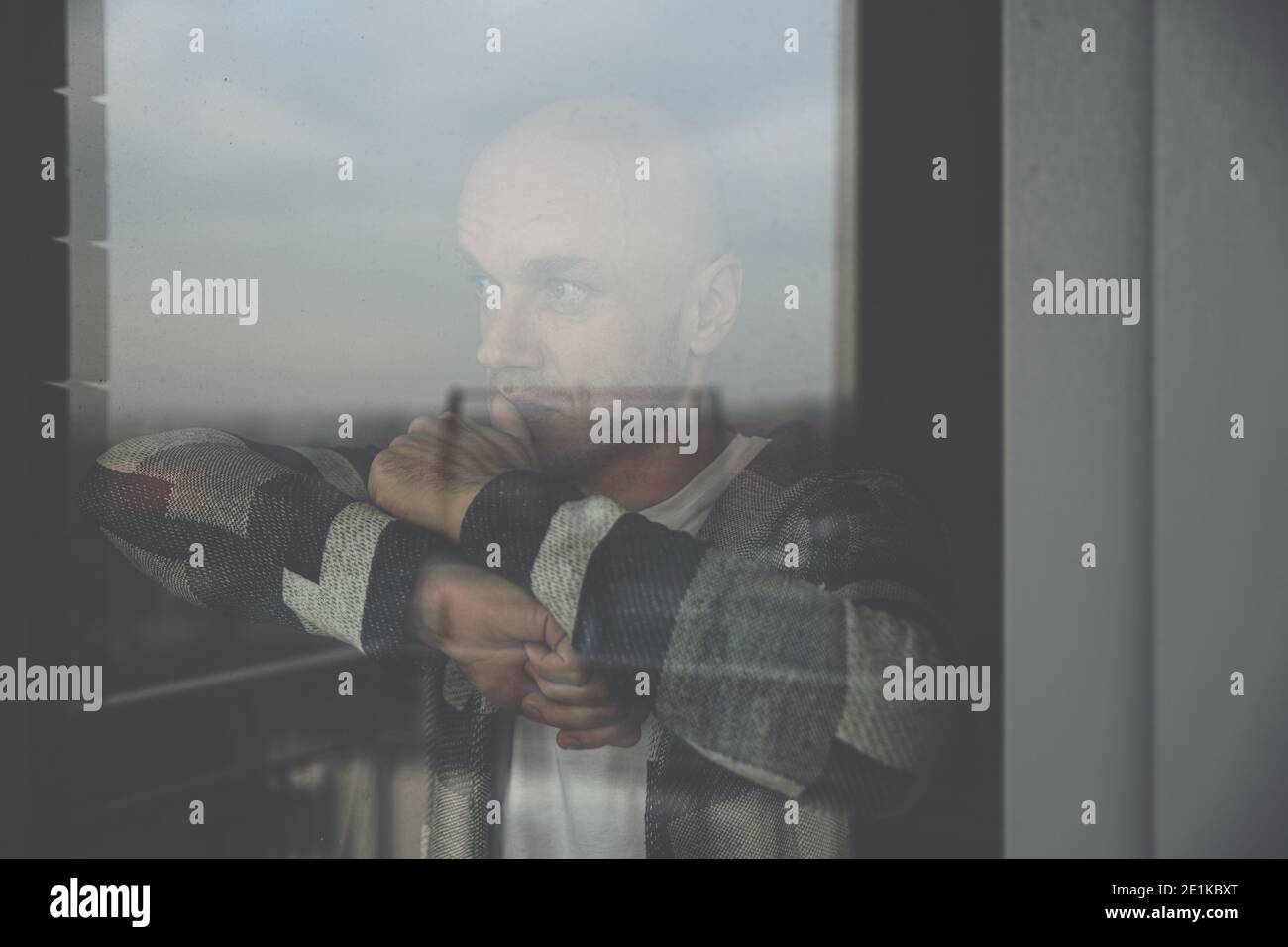 Sad young man looking through the window. Stock Photo