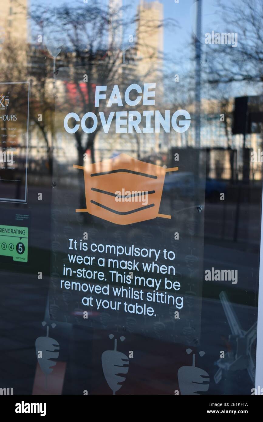 Notice in restaurant window stating that face coverings must be worn. Stock Photo