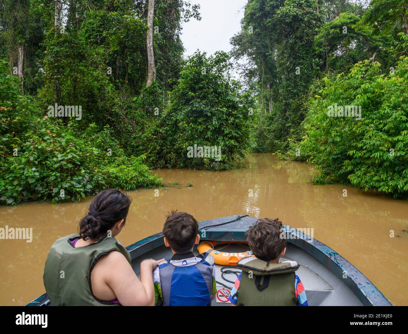 family on a river raft cruise in the Sukau Rainforest Stock Photo