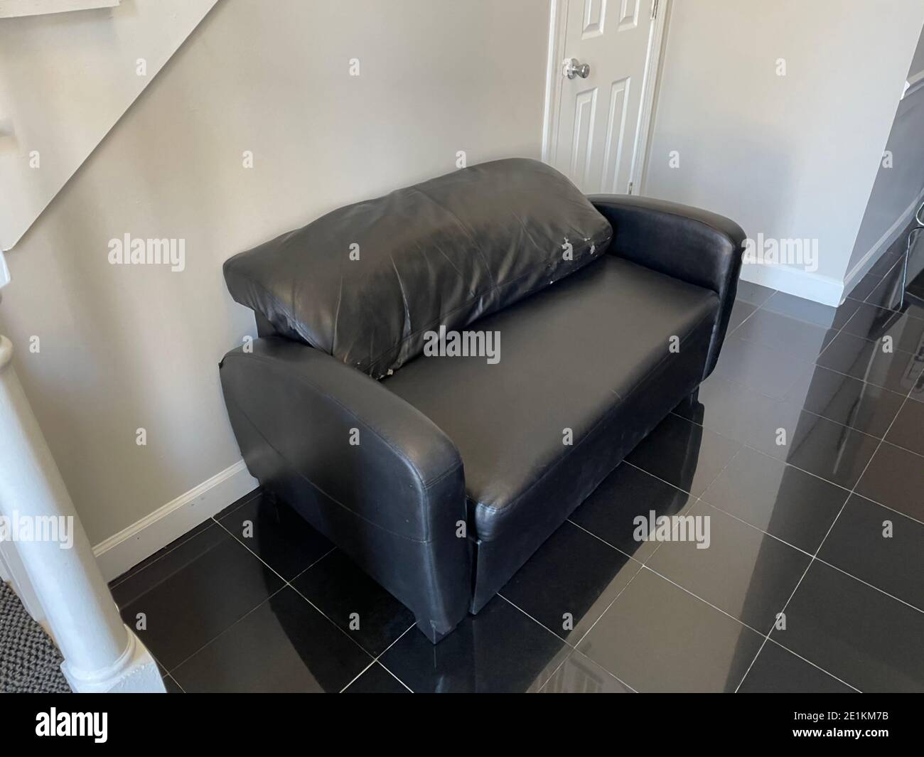 View of a rough looking black sofa couch in a business office lobby