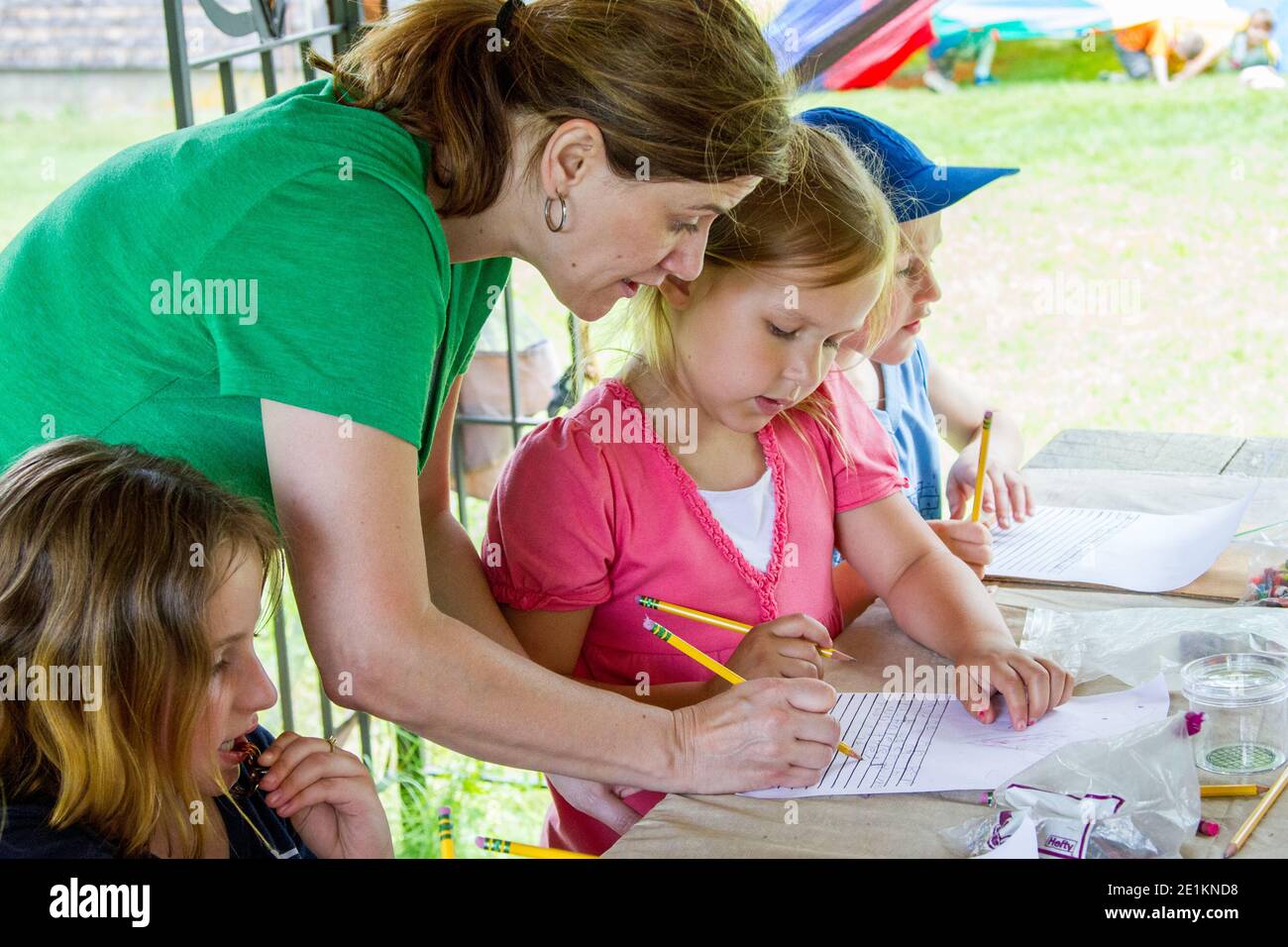 A teacher helping students at an outdoor classroom Stock Photo