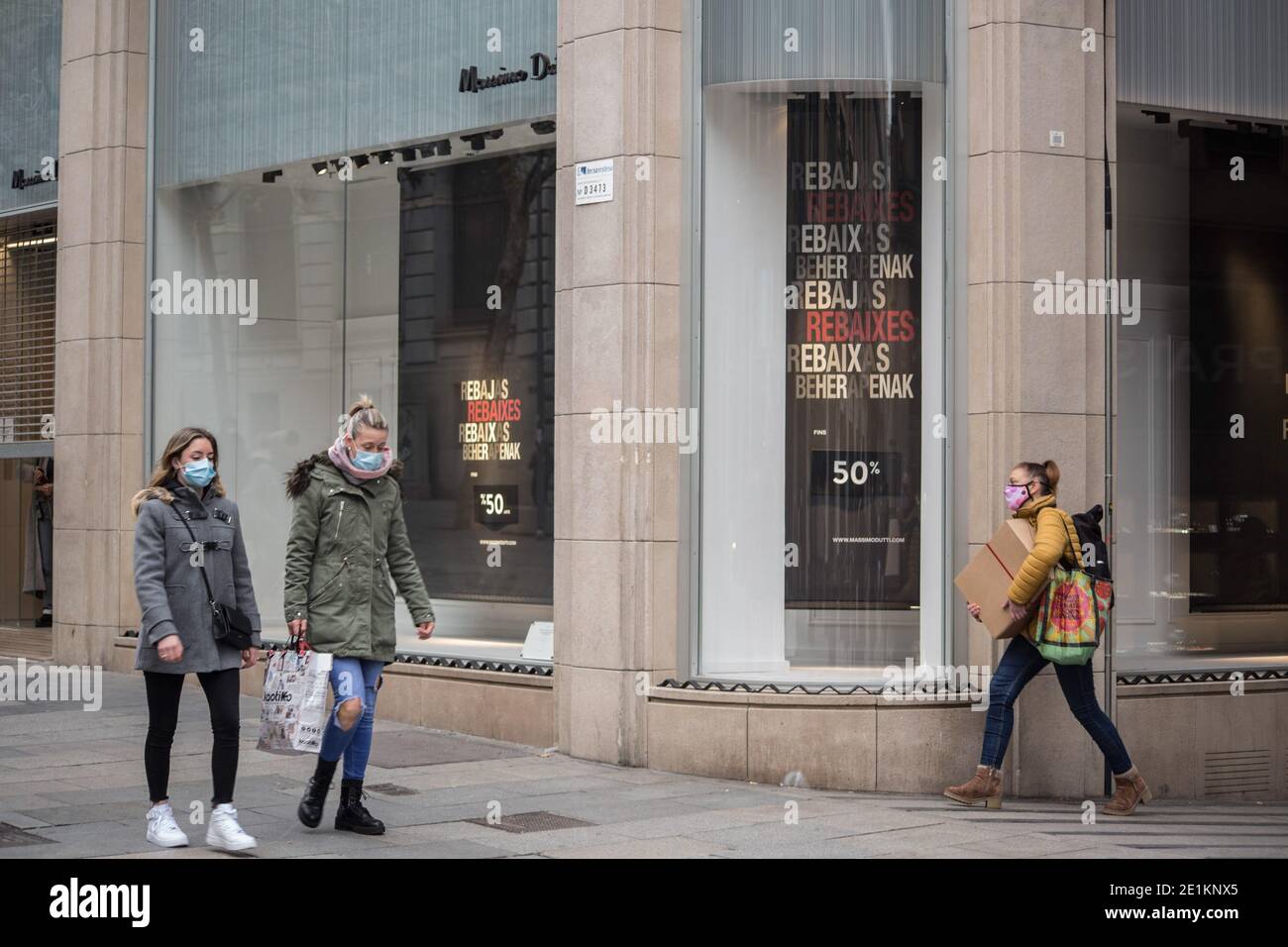 Barcelona, Spain. 07th Jan, 2021. People wearing face masks walk past Massimo  Dutti store with a sales poster. The sales season begins in Barcelona this  January 7, having to comply with the