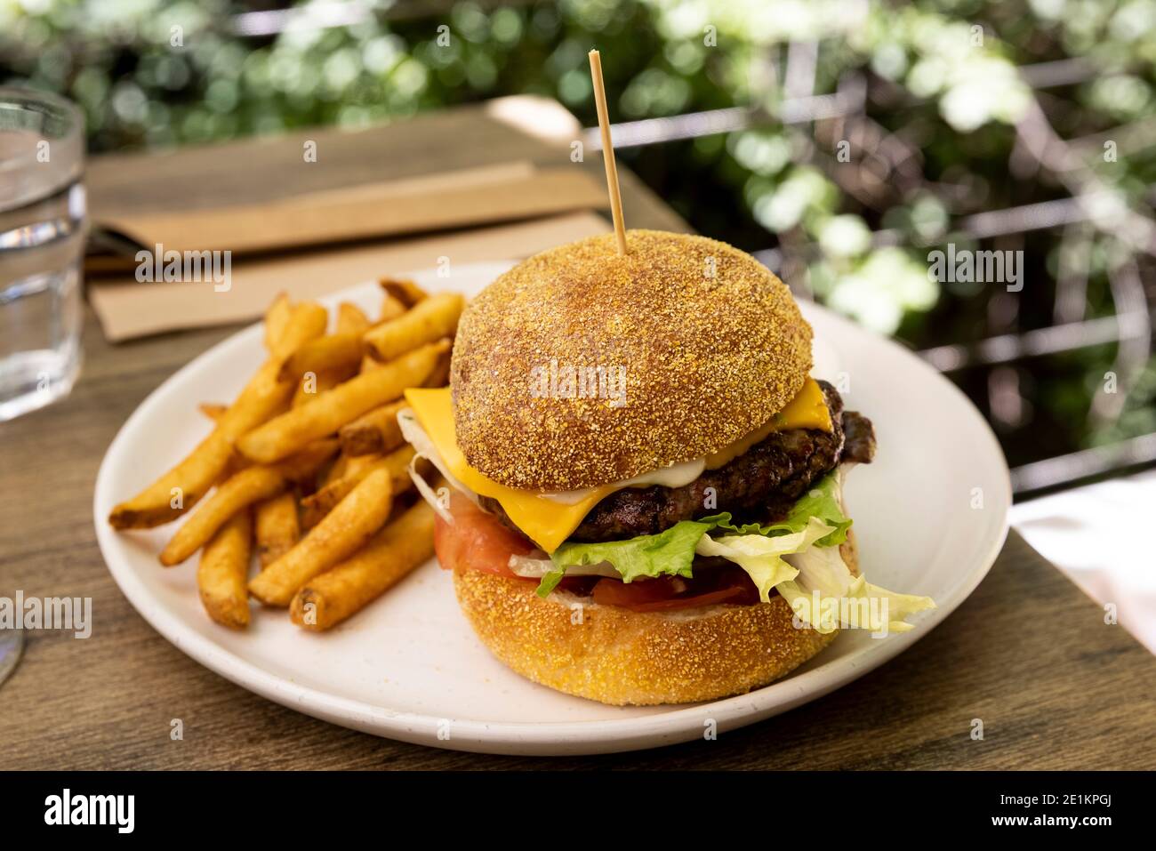A delicious cheeseburger and fries served on an outside table Stock Photo