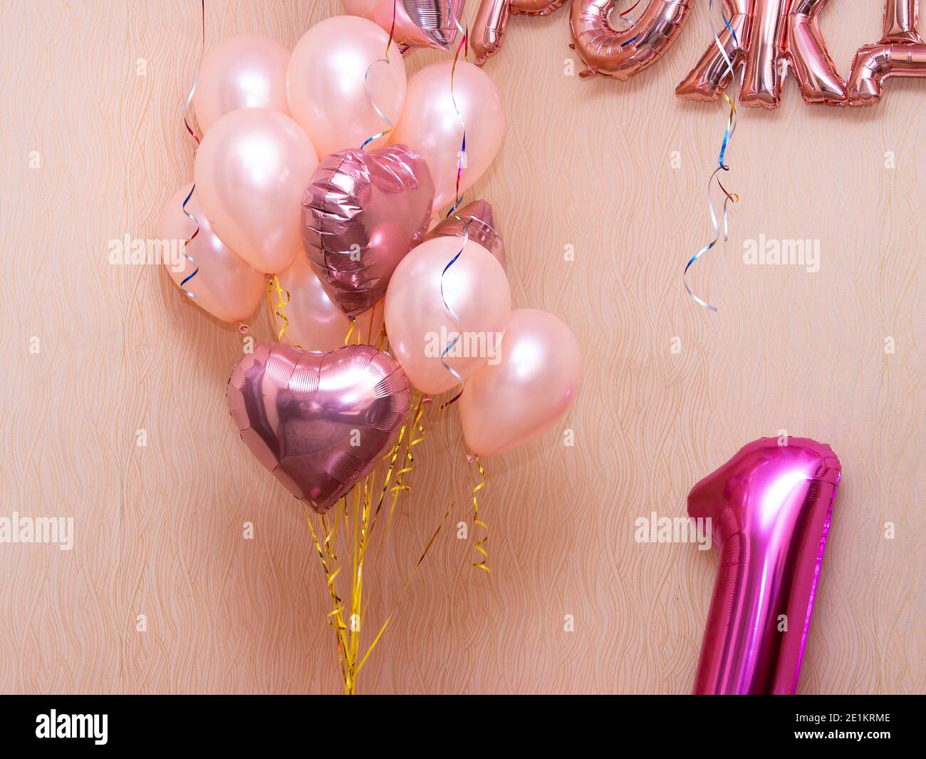 several pink helium balloons, inflatable letters on the wall, and an ...