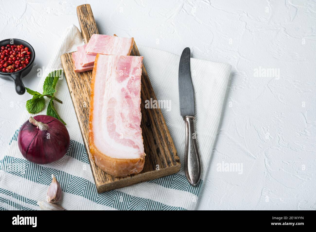 Bacon pancetta cut and sliced with herbs on white background with space