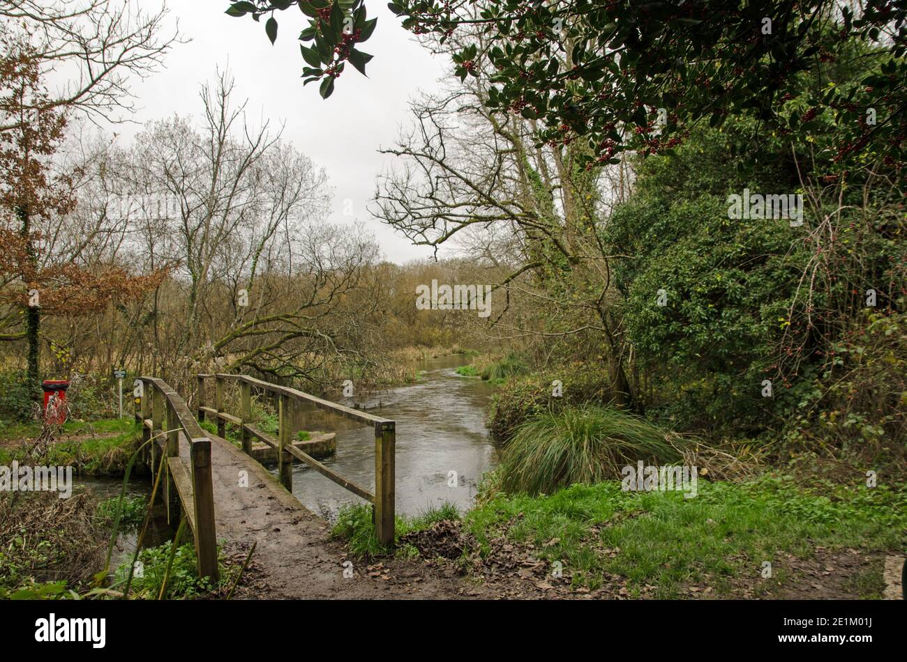 Footbridge over a bend in the River Itchen in the village of Itchen Stoke, Hampshire on a cloudy autumn day. Stock Photo