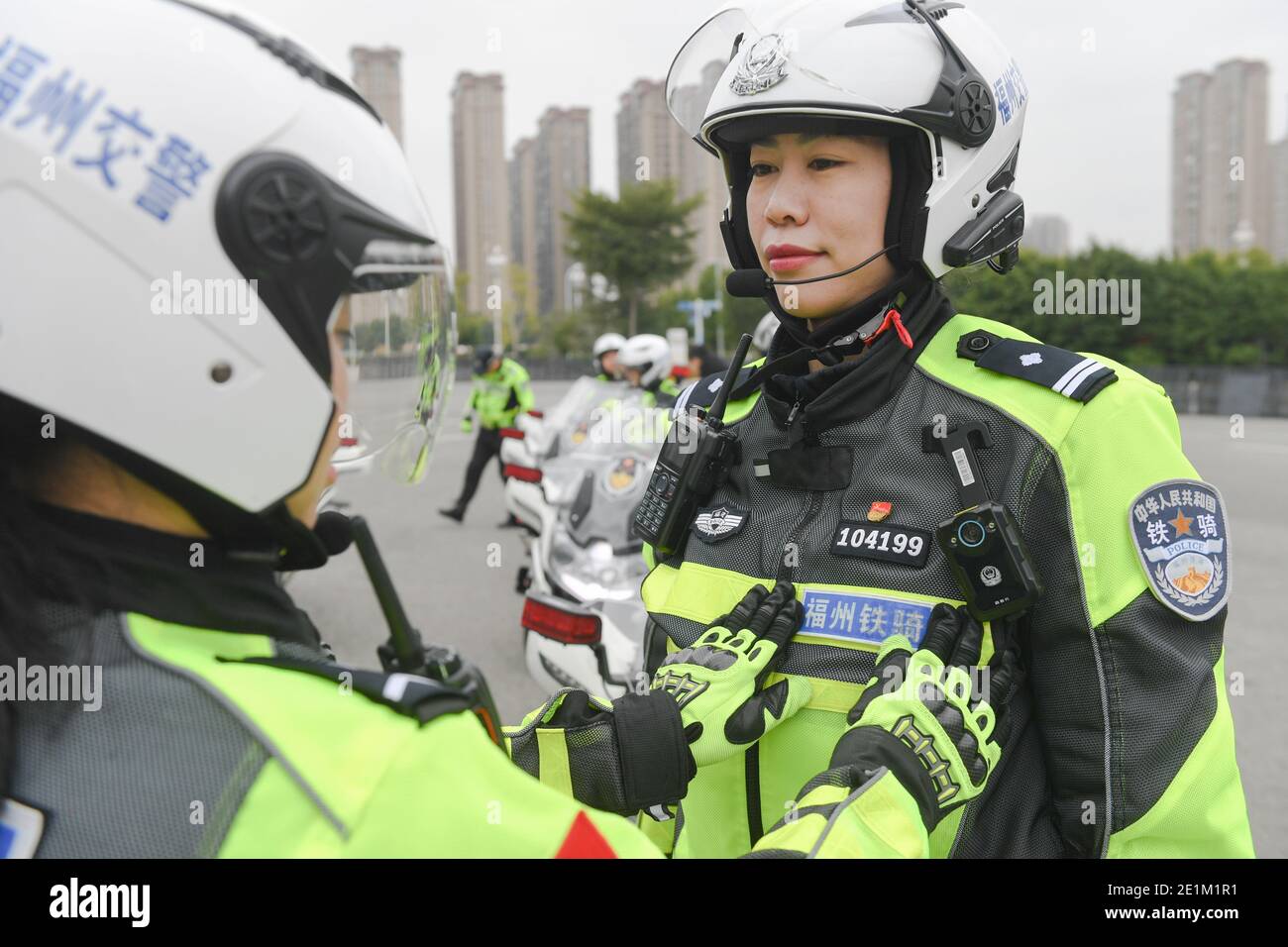 (210108) -- FUZHOU, Jan. 8, 2021 (Xinhua) -- Wang Hanxin, head of a traffic policewomen motorcycle team, arranges her uniform with the help of her colleague in Fuzhou City, southeast China's Fujian Province, Jan. 7, 2021.  The city's first traffic policewomen motorcycle team was established days before the upcoming first Chinese police day that is set on Jan. 10, 2021.   With an average height of up to 1.7 meters, those  female motorcyclists in handsome uniforms are well-trained to be able to drive the about 300 Kg police motorcycle to perform duty, never failing to attract attentions wherever Stock Photo