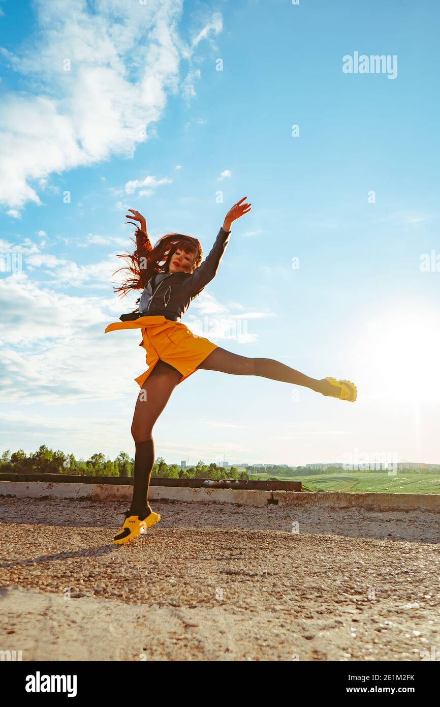 a yellow girl in a skirt jumps high with her legs spread out like a  ballerina against the sky Stock Photo - Alamy