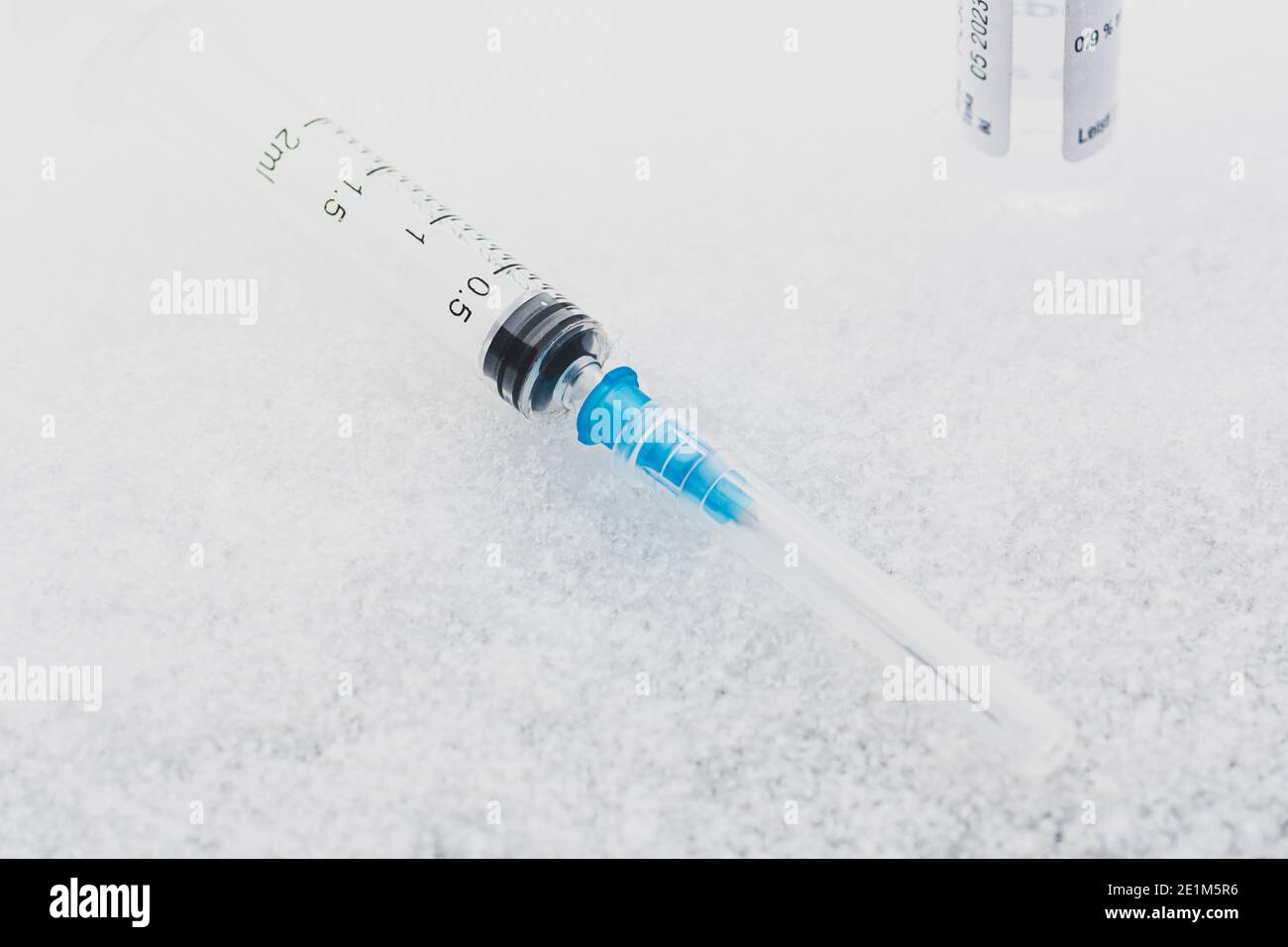 Syringe and vial ready to be used on the ice or snow. Covid or Coronavirus vaccine background Stock Photo