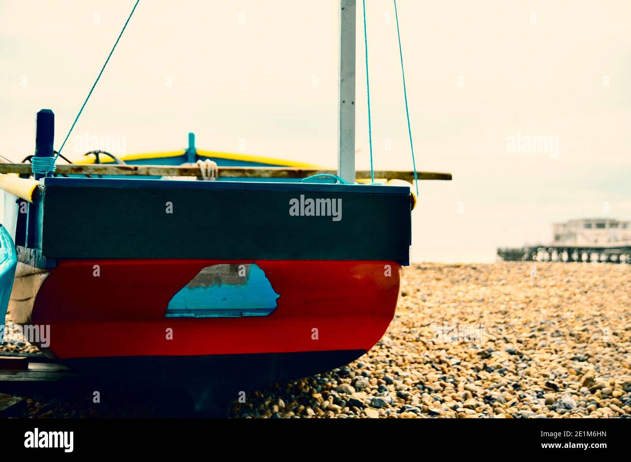 Wooden fishing boat on pebble beach U.K England. Seaside scene pier in background. old fashioned