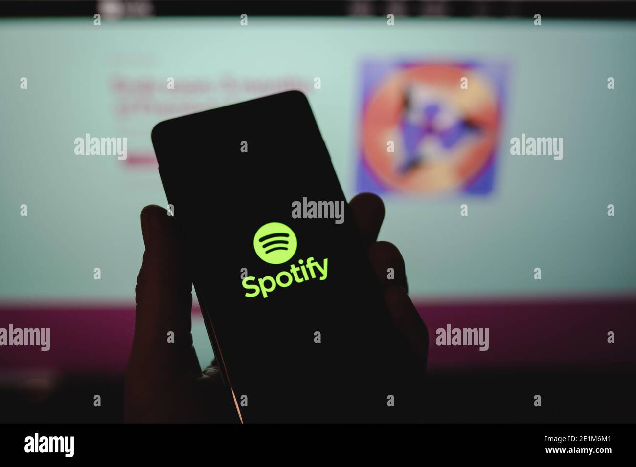 Man holding a smartphone with Spotify logo in front of the official website Stock Photo